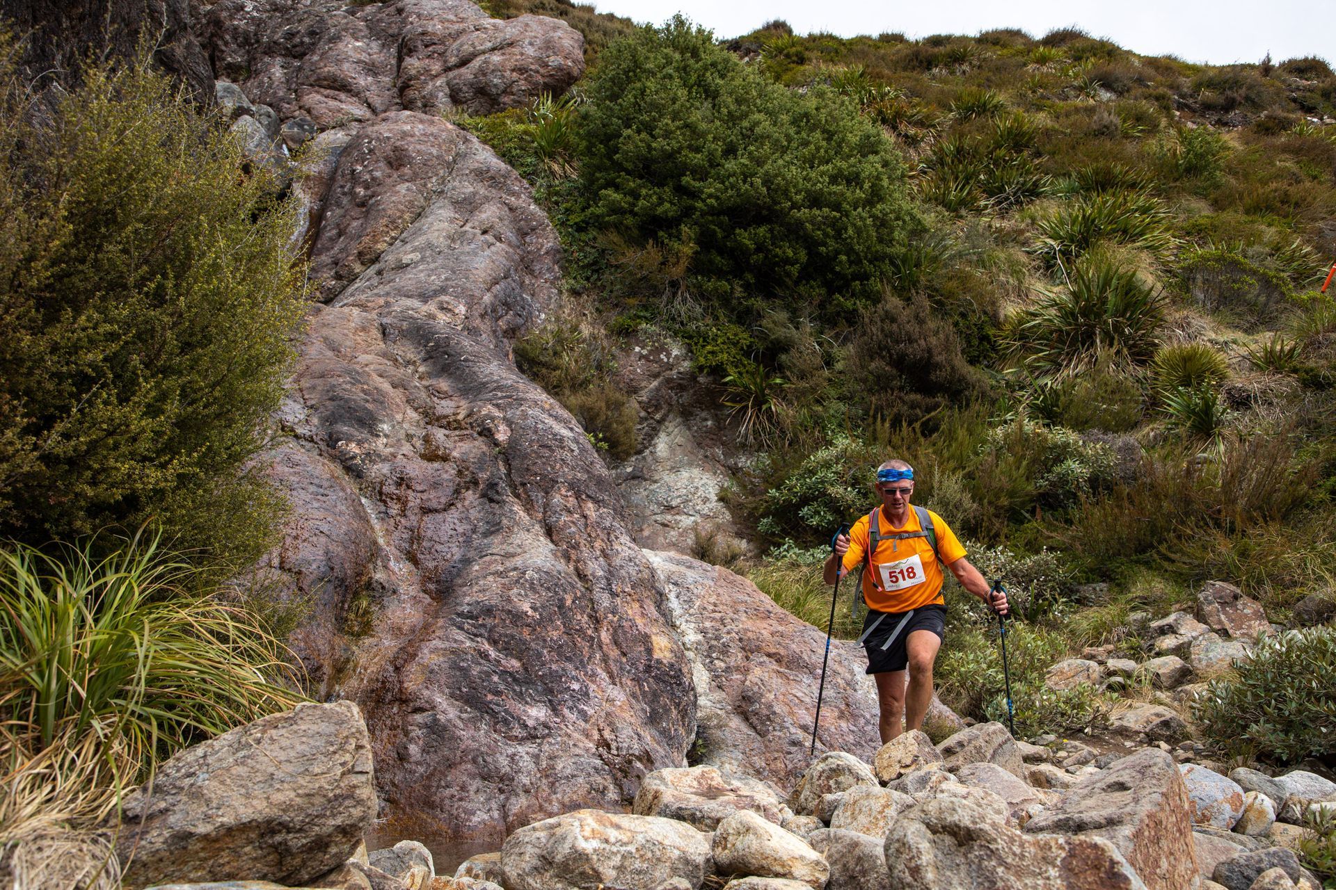 A man is walking across a rocky hillside.