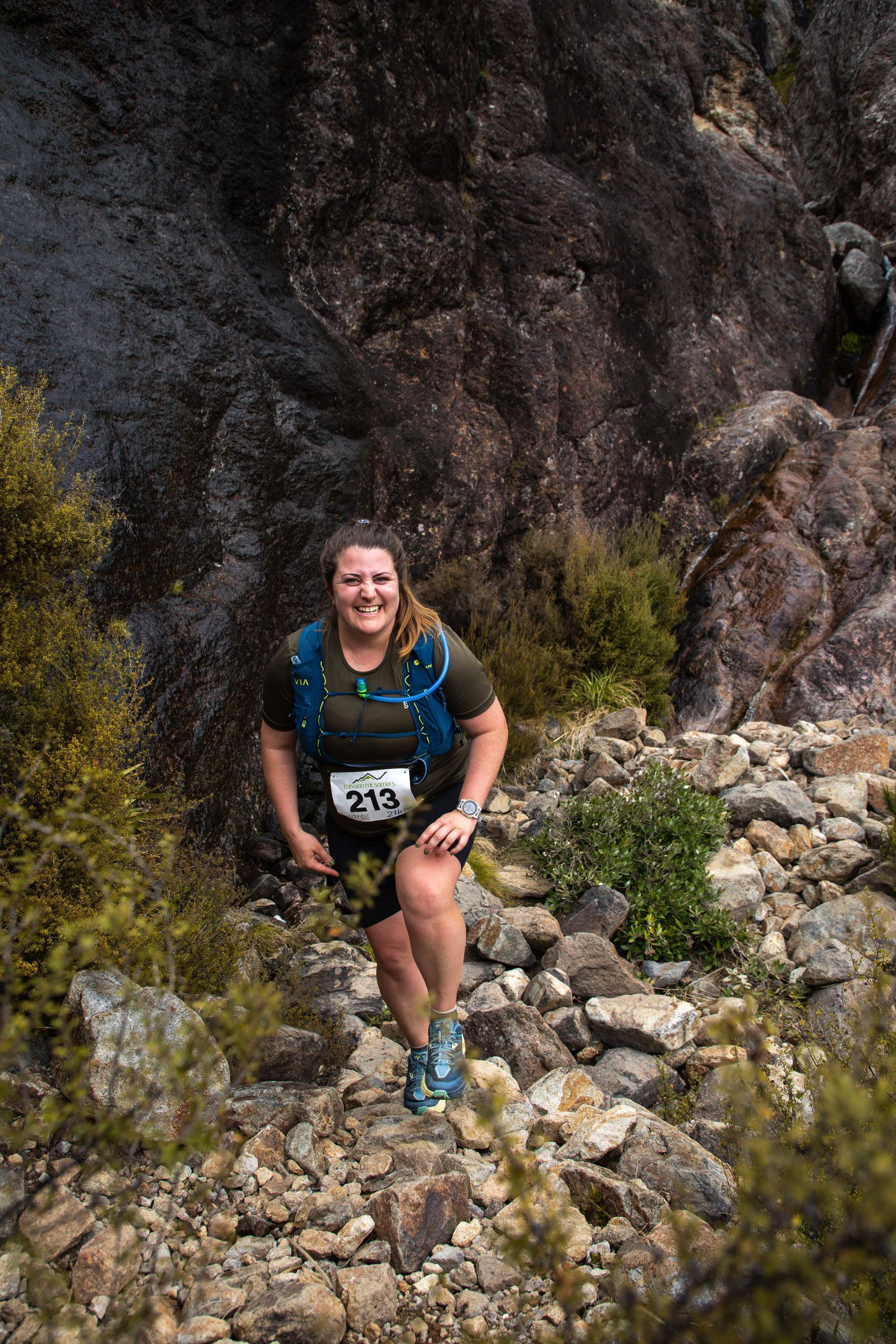 A woman is walking up a rocky hillside.