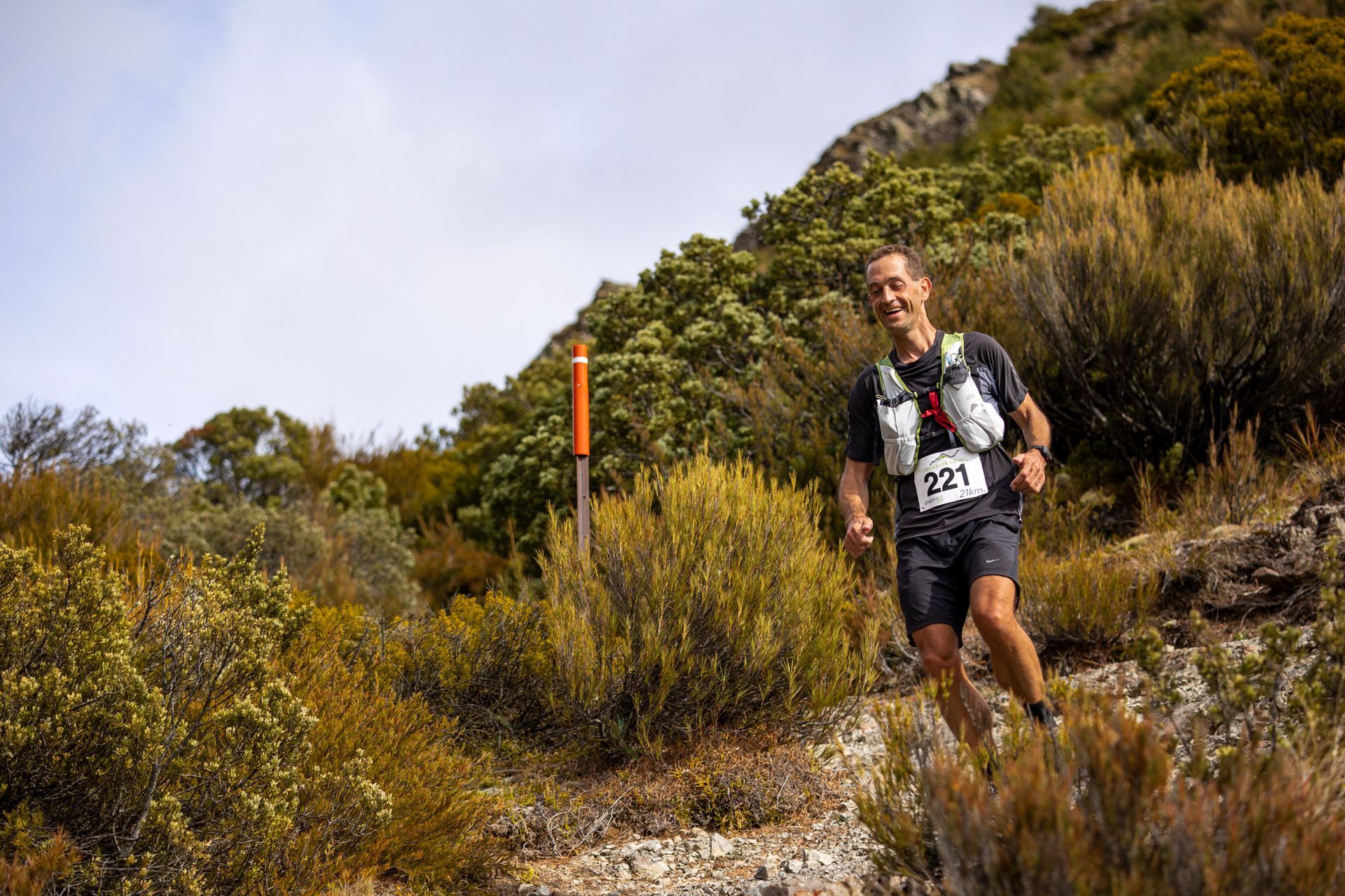 A man is running up a hill in the woods.