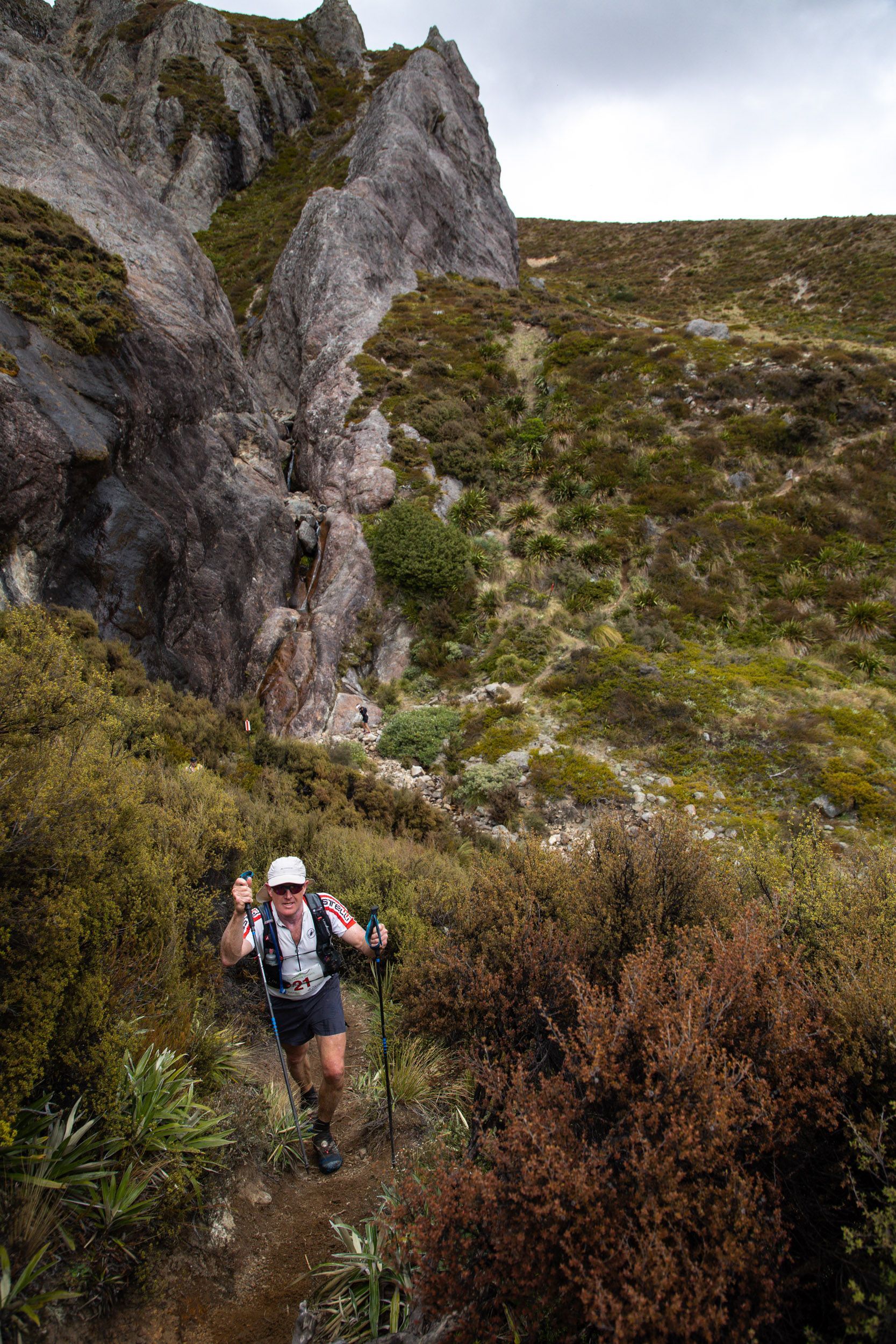 A man is hiking up a hill with a backpack.