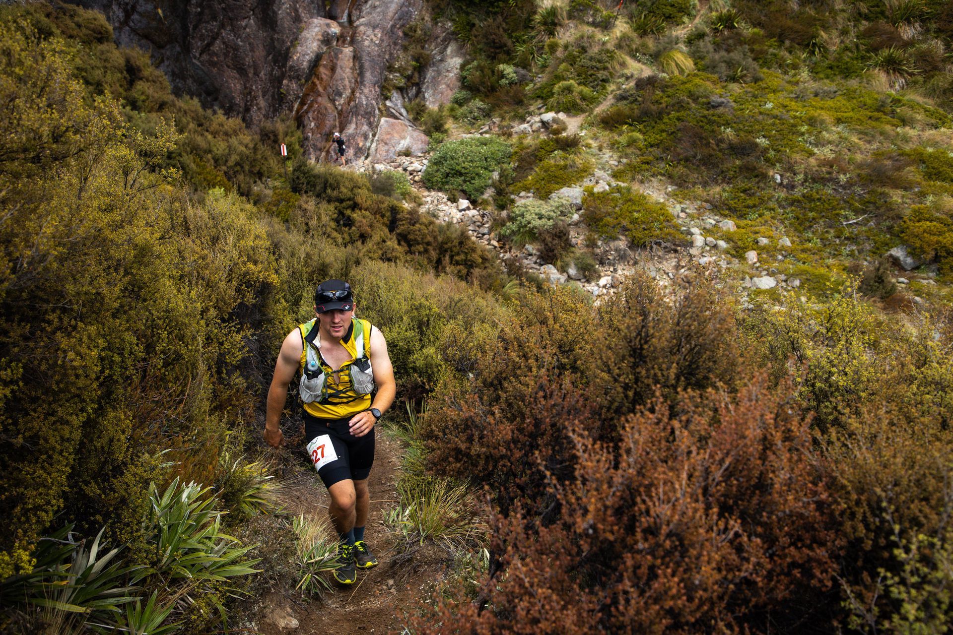 A man is running down a trail in the woods.