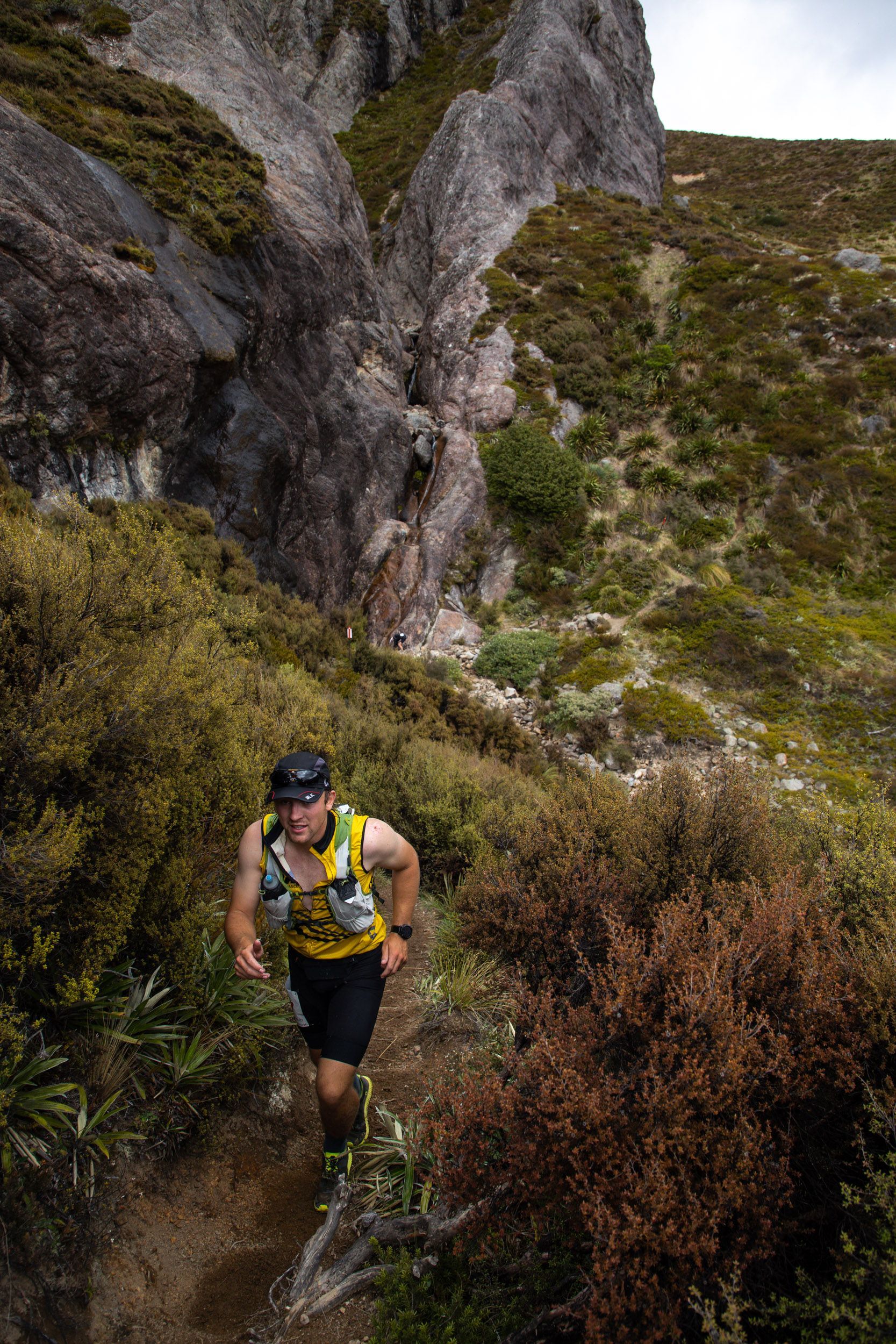 A man is running down a trail on a mountain.