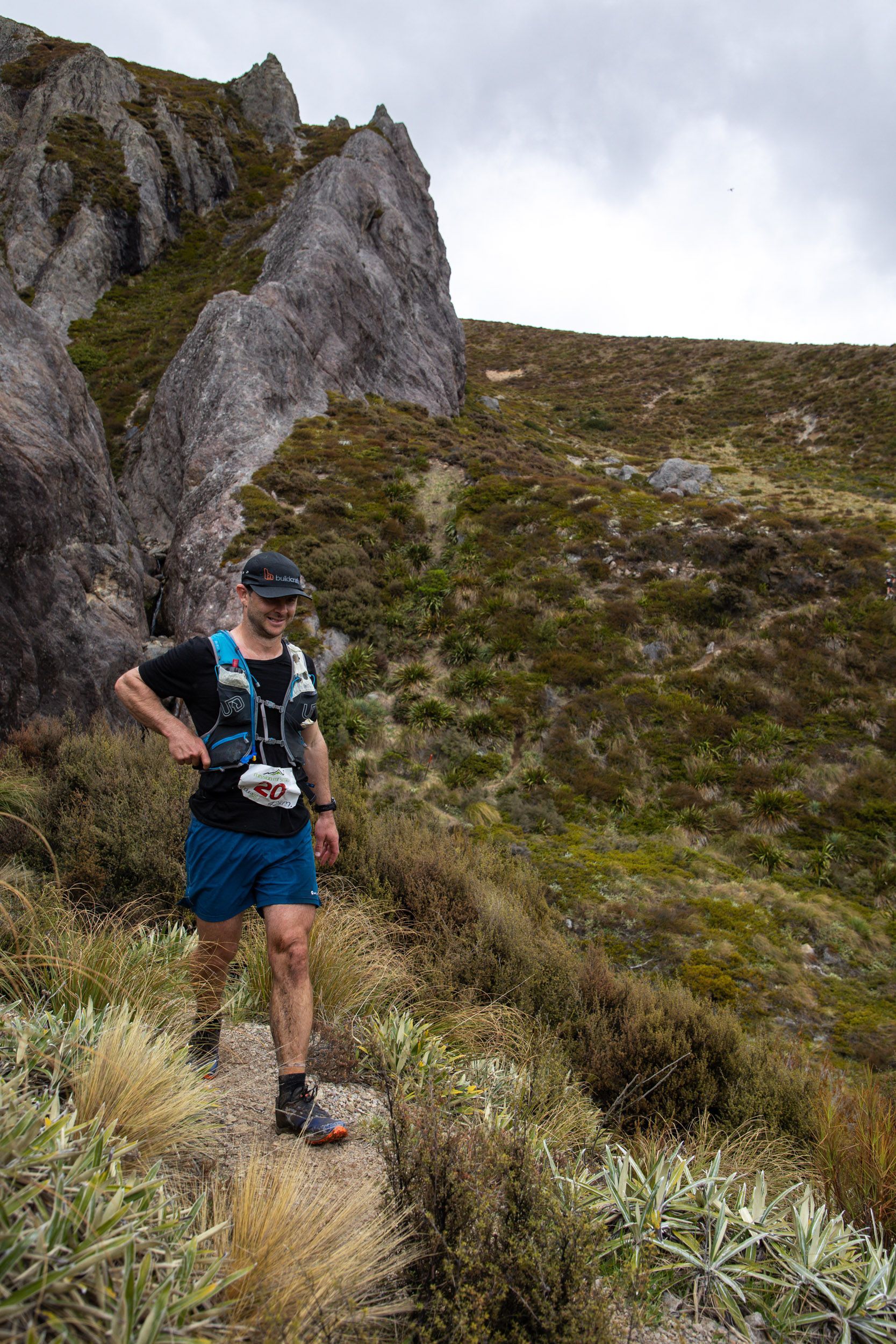 A man is running on a trail in the mountains.