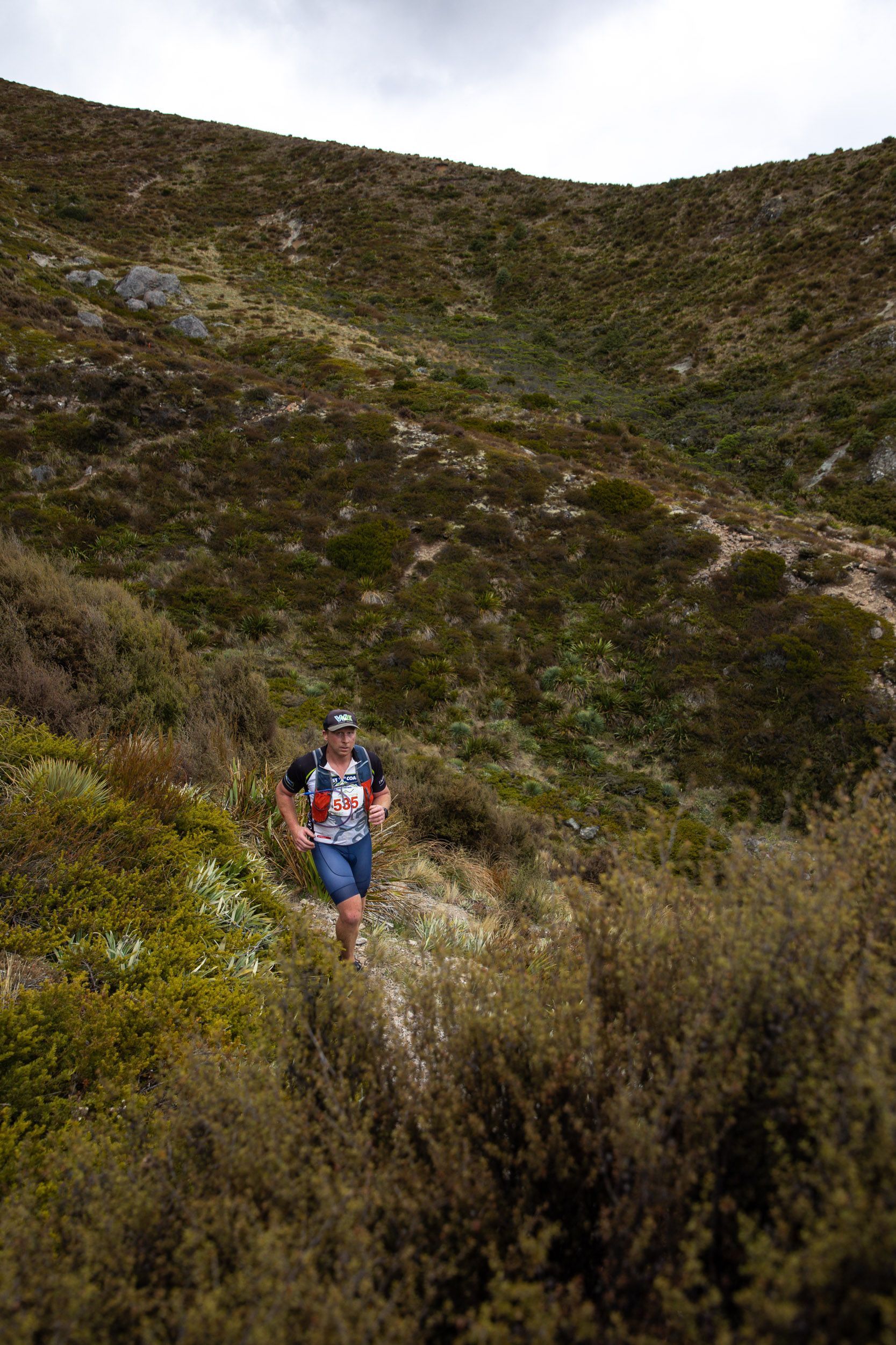A man is running down a hill on a trail.