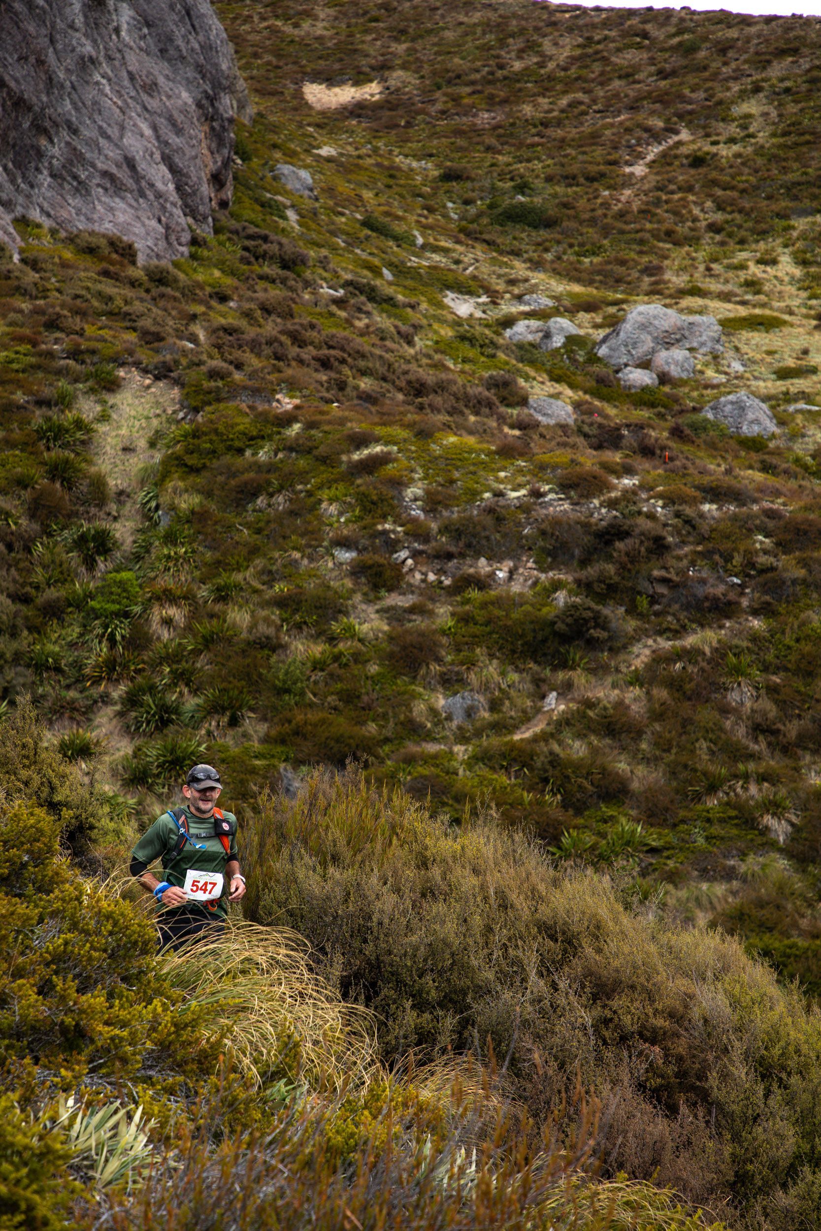 A man is running down a hill in the woods.
