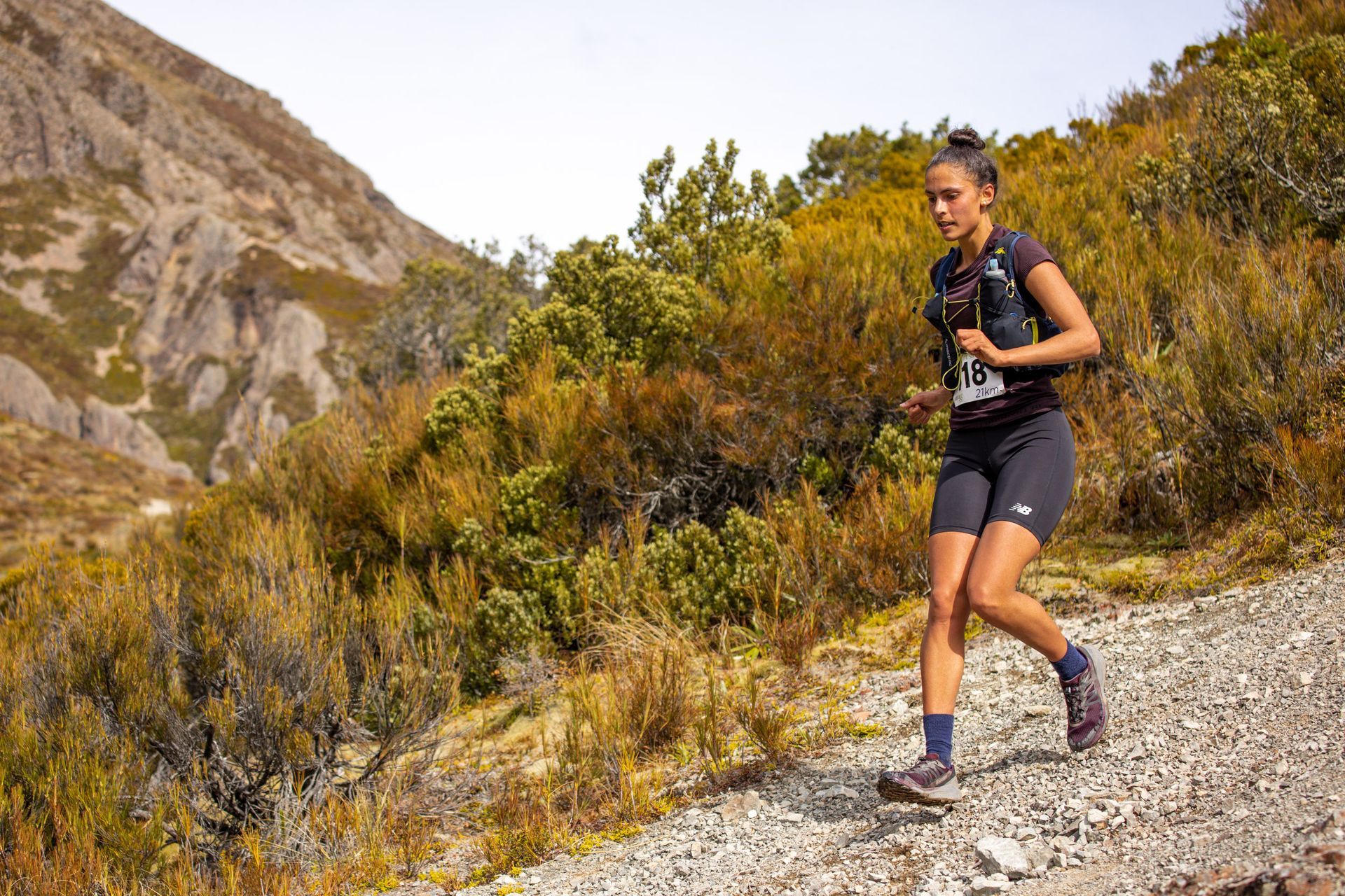 A woman is running on a trail in the mountains.