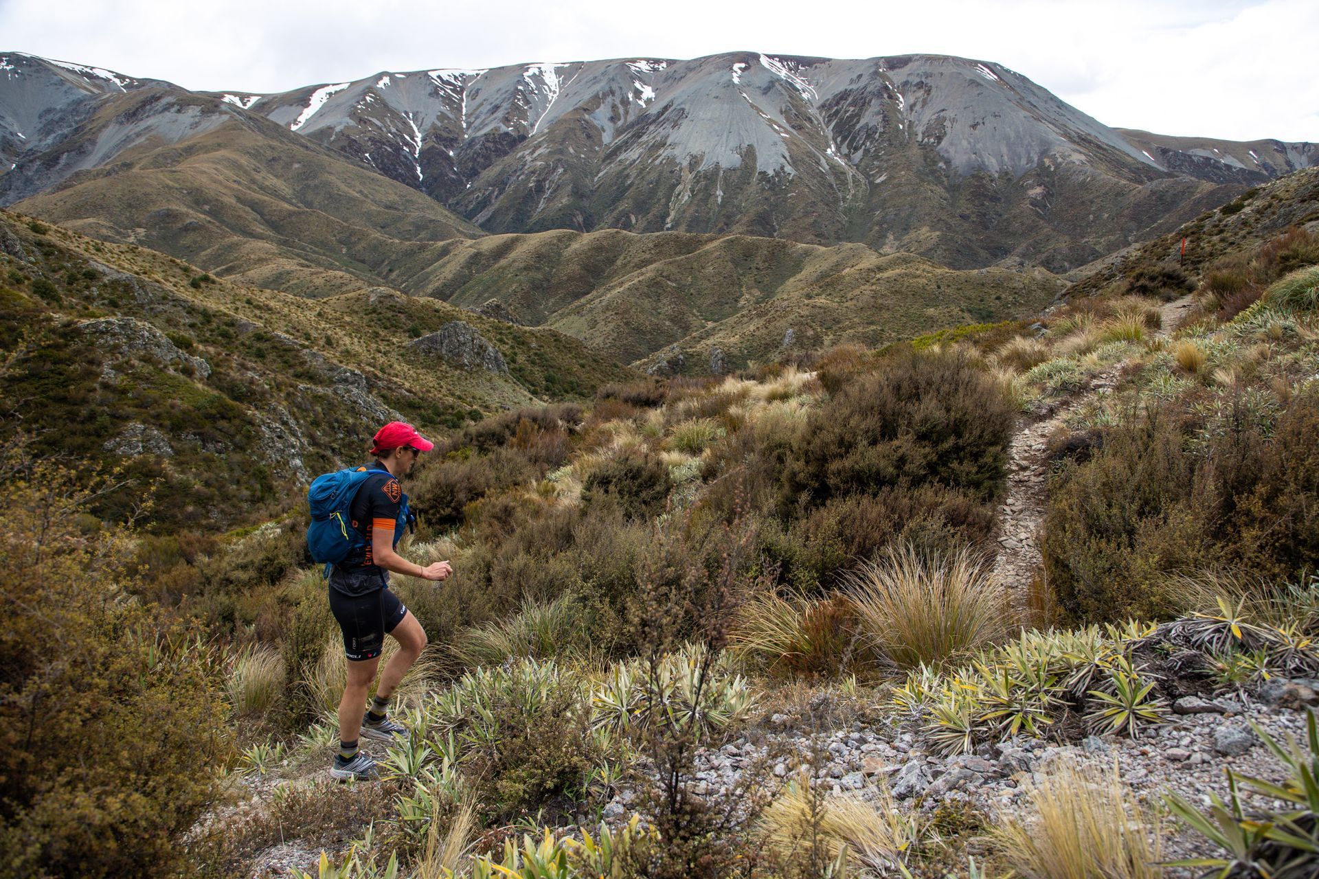 A person with a backpack is walking down a trail in the mountains.