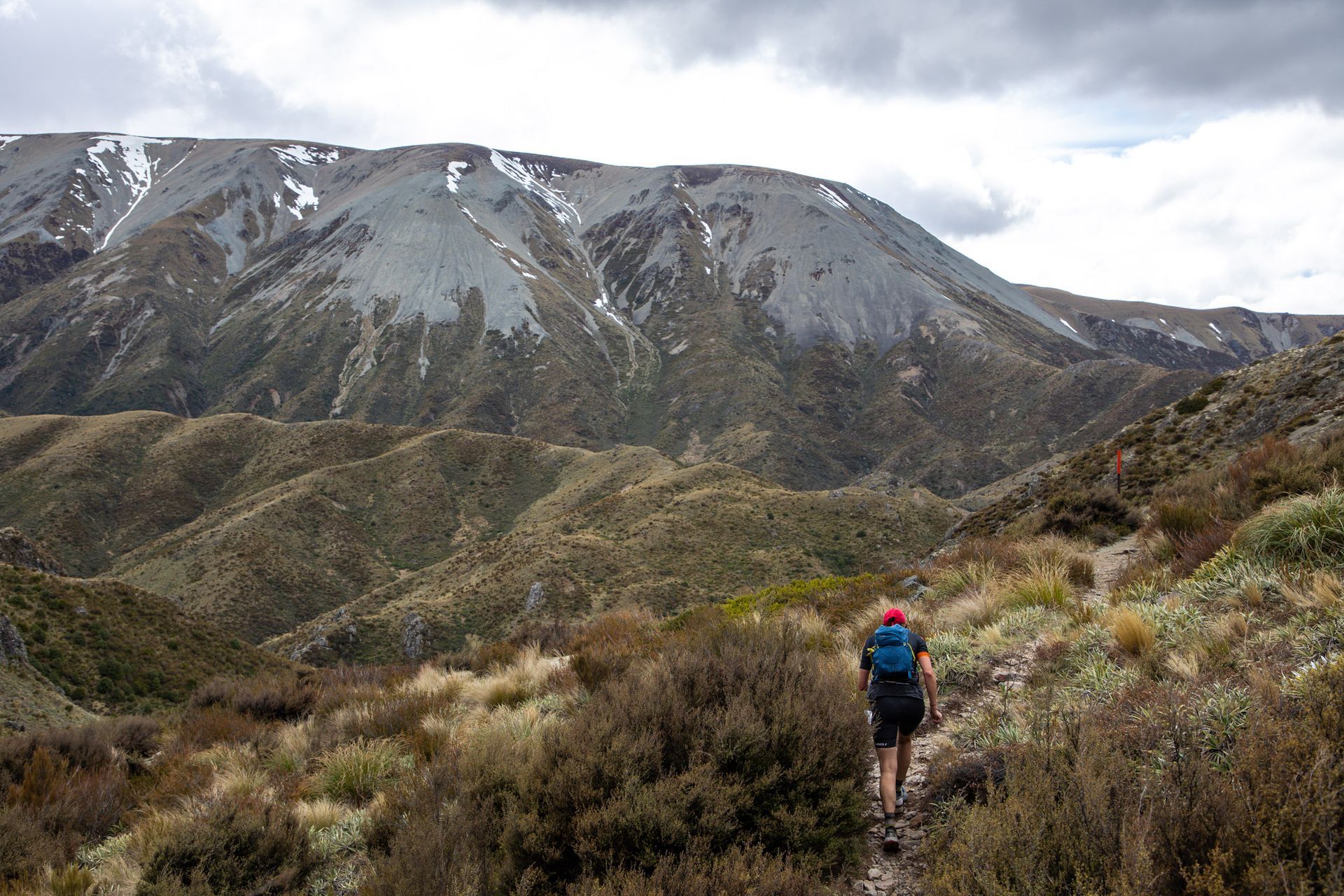 A person with a backpack is walking on a trail in the mountains.