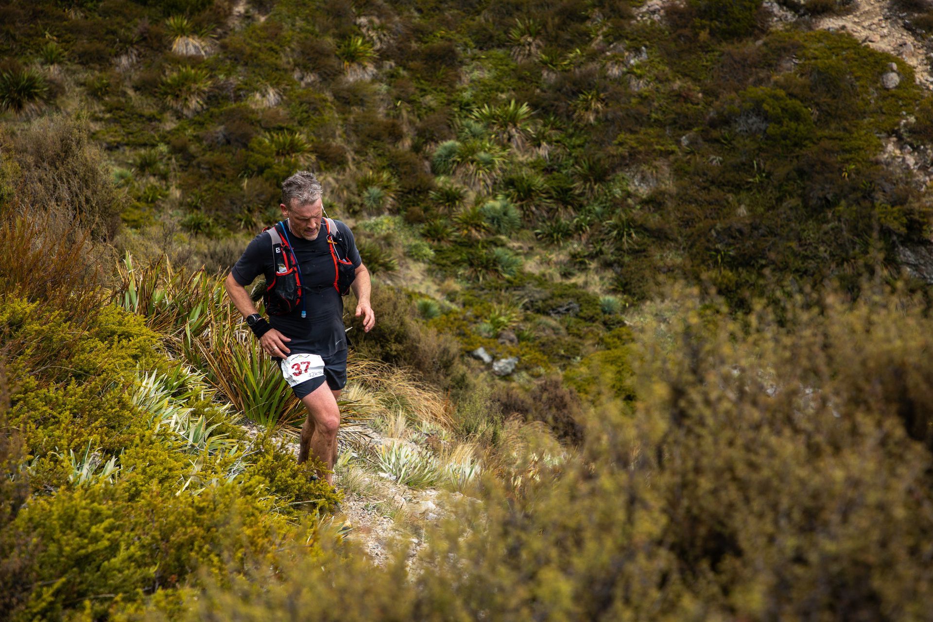 A man is running up a hill in the woods.
