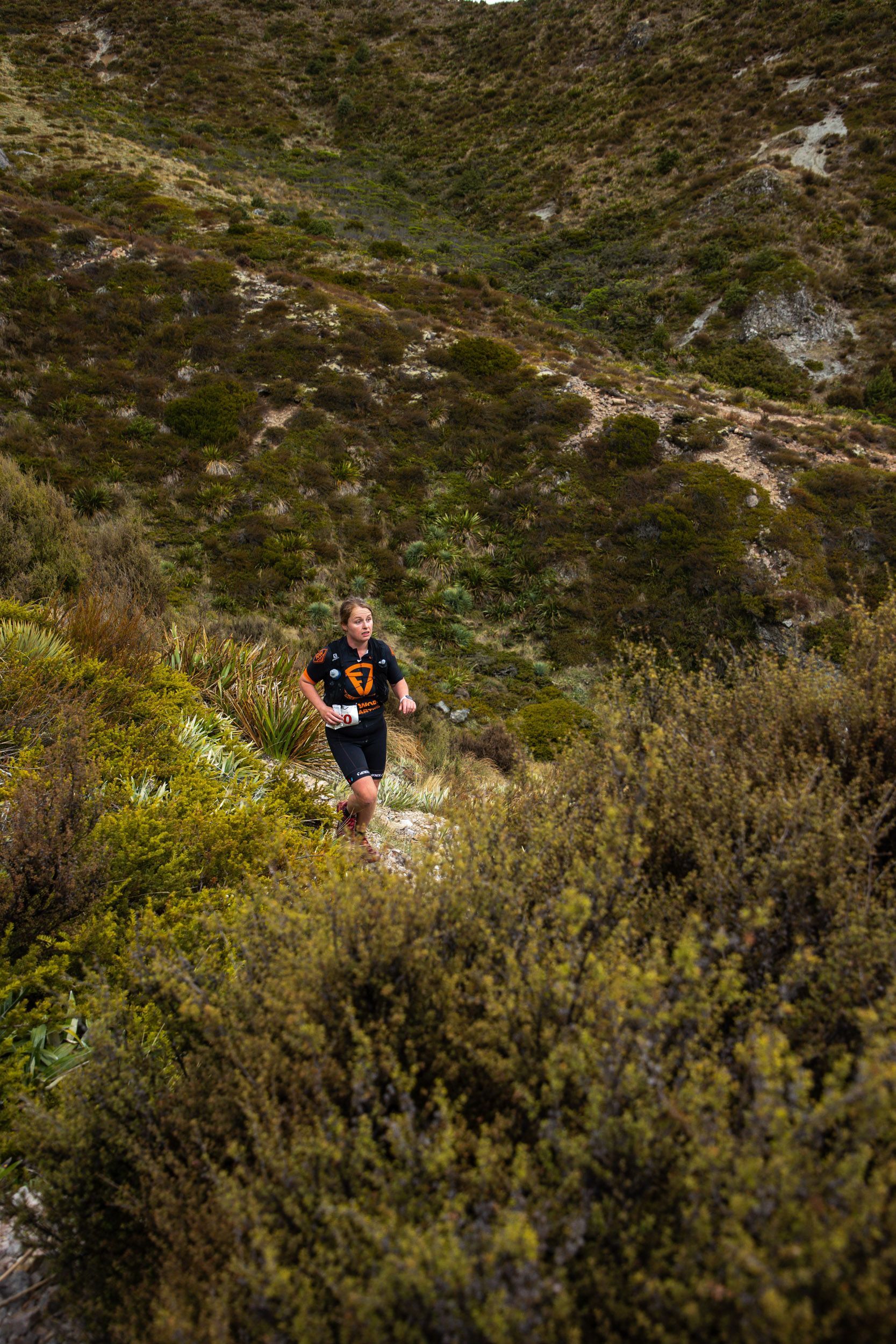 A man is running up a hill in the woods.
