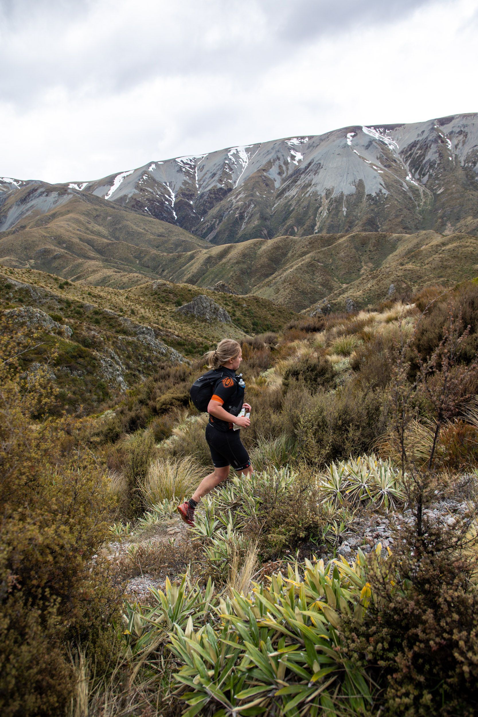 A man is running down a trail in the mountains.