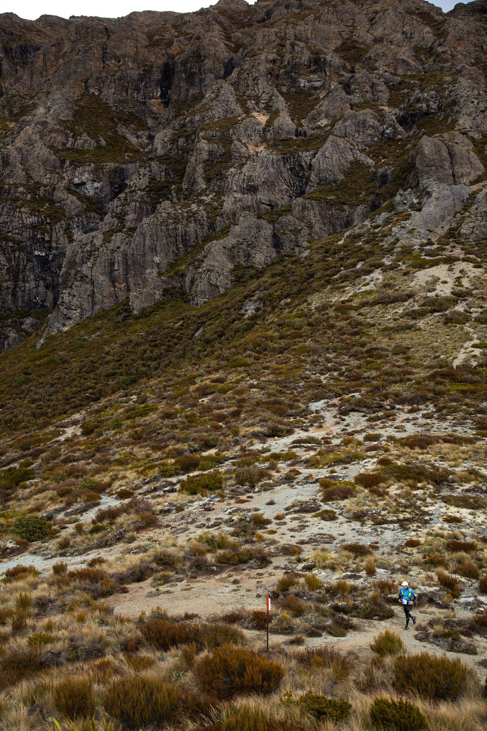 A person is walking down a dirt path in the mountains.