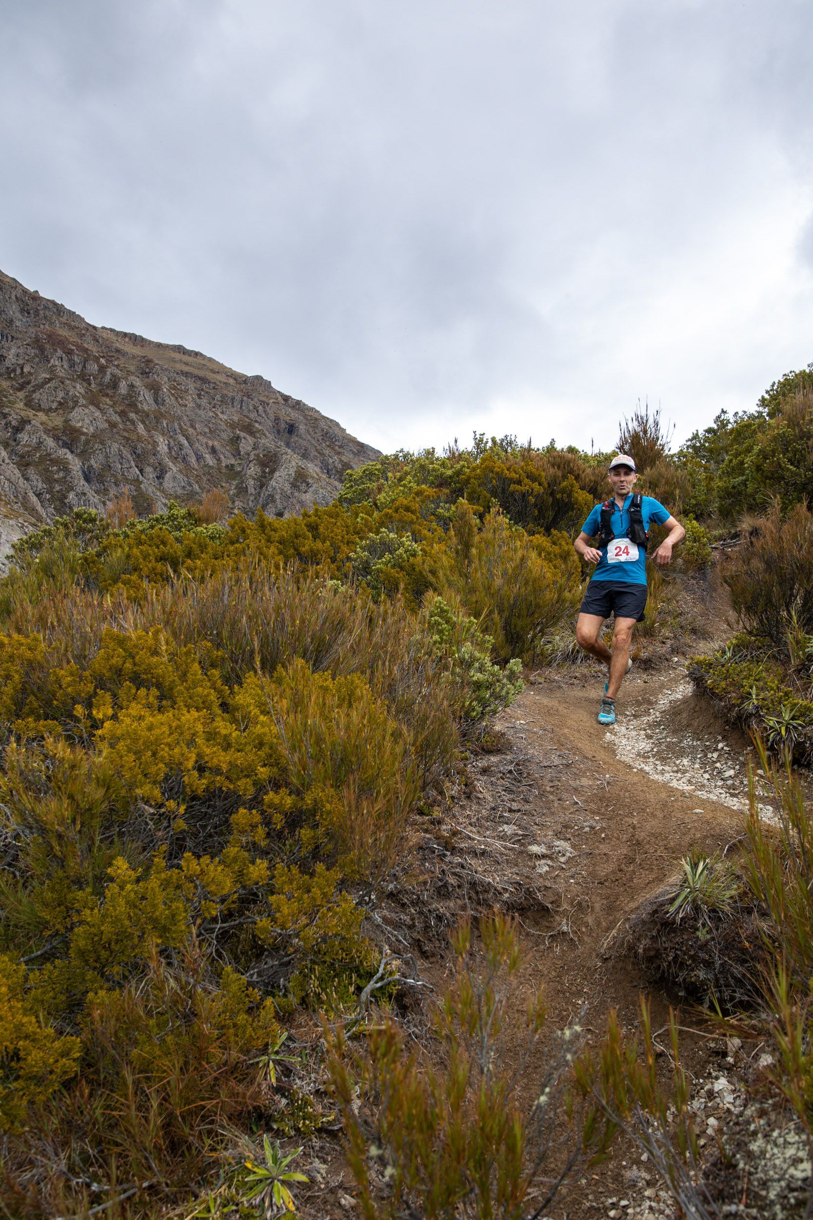 A man is running on a trail in the mountains.