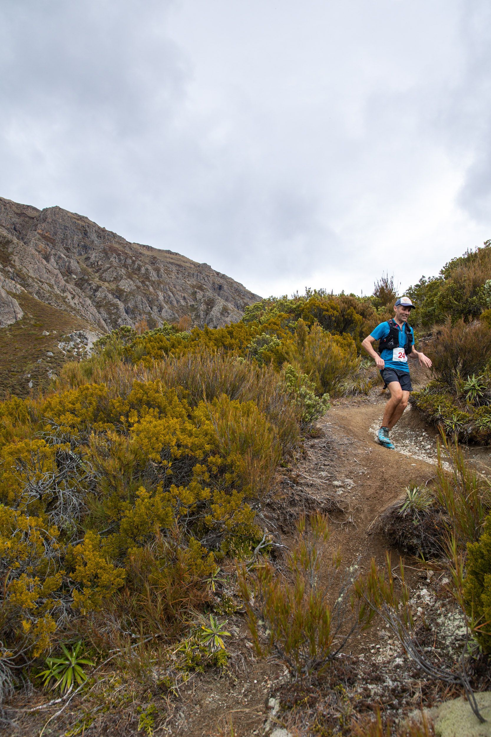 A man is running on a trail in the mountains.