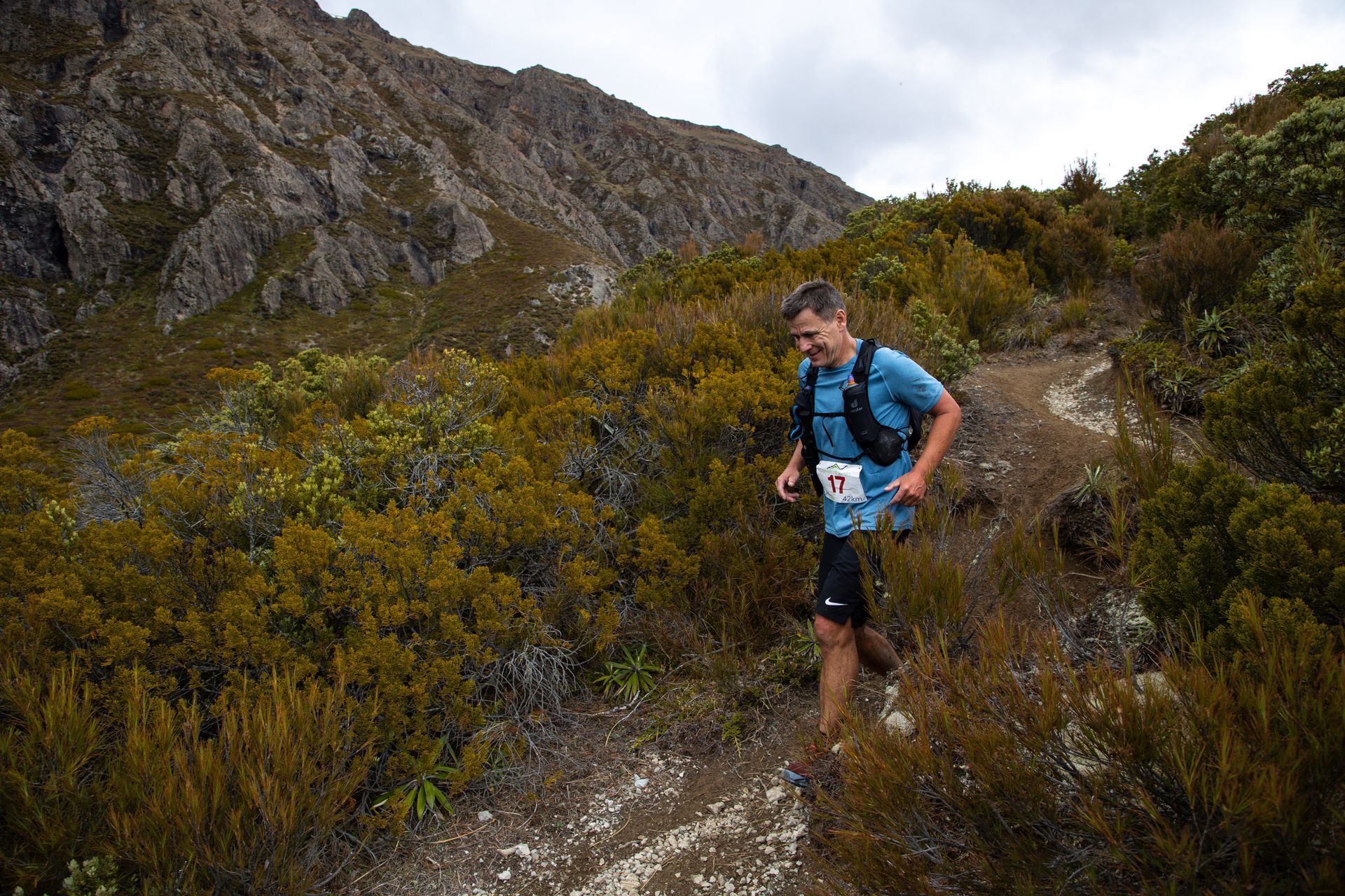 A man is running on a trail in the mountains.