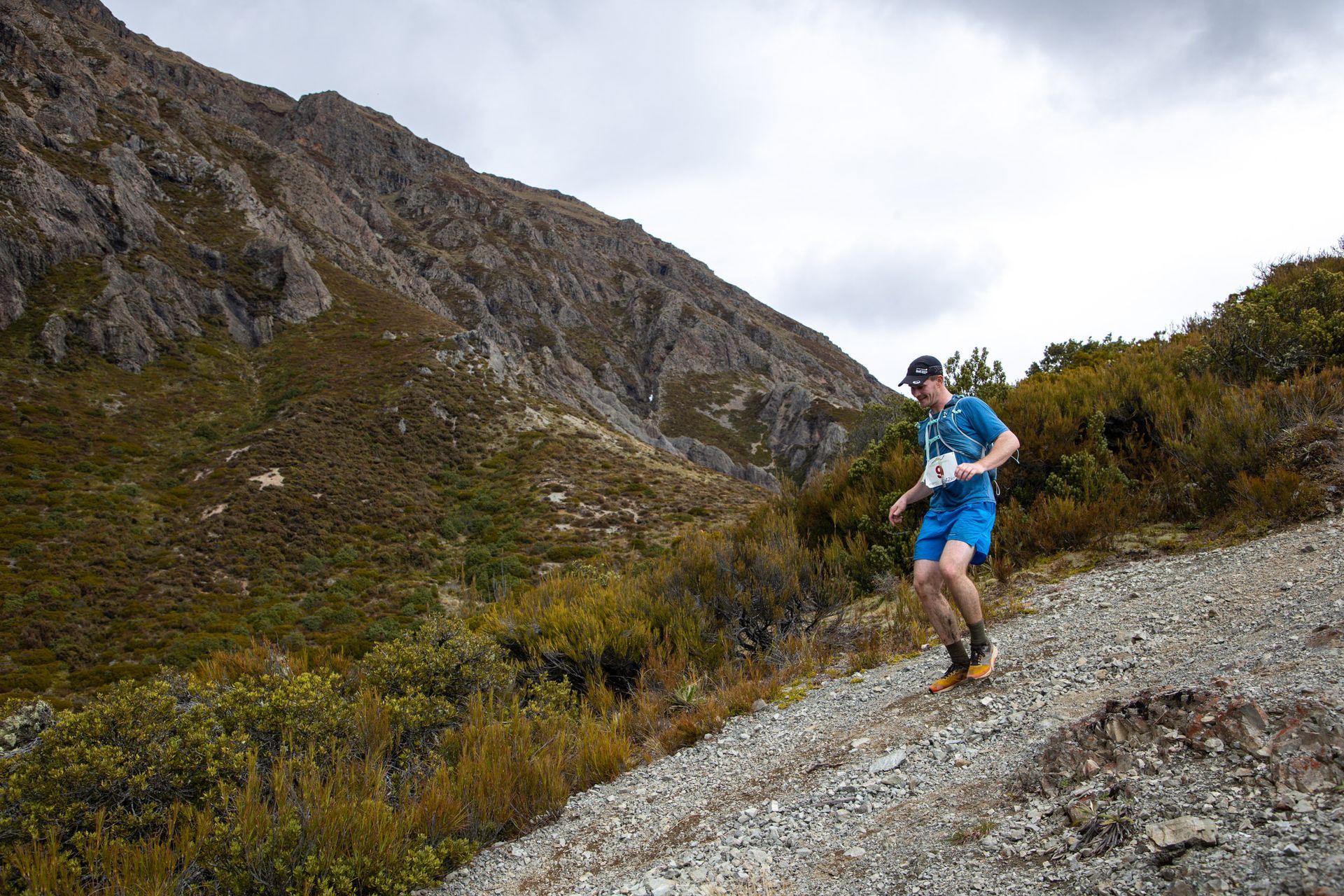 A man is running down a dirt road in the mountains.