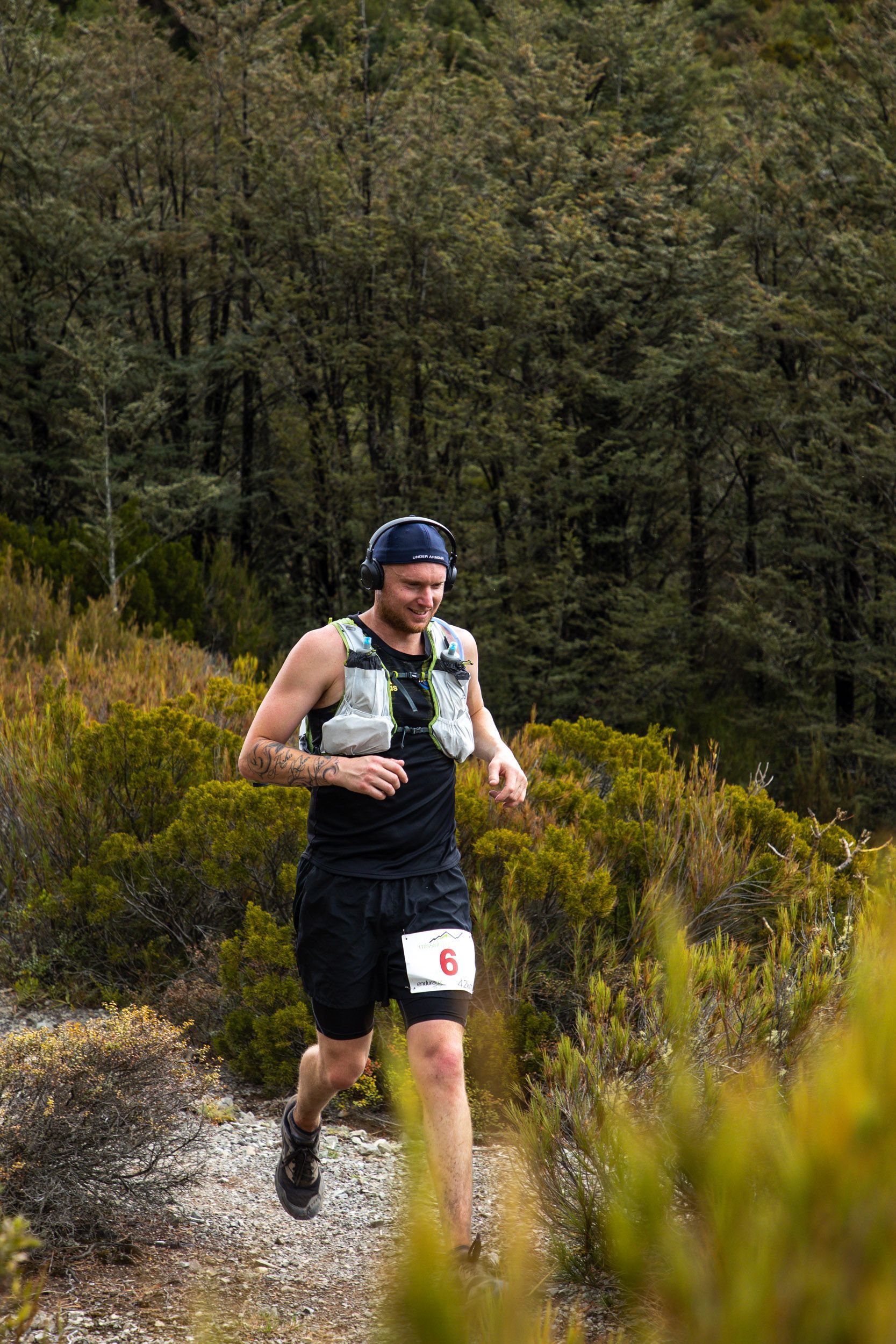 A man is running on a trail in the woods.