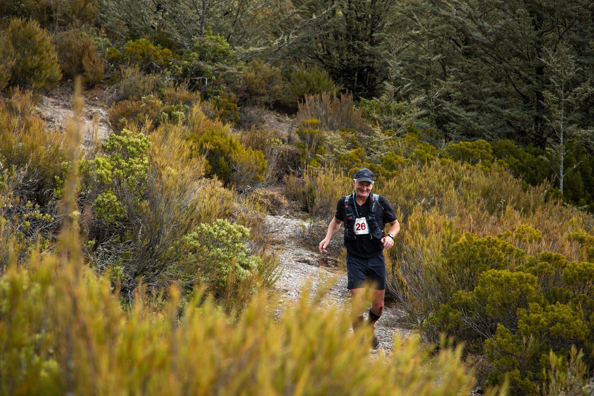 A man is running on a trail in the woods.