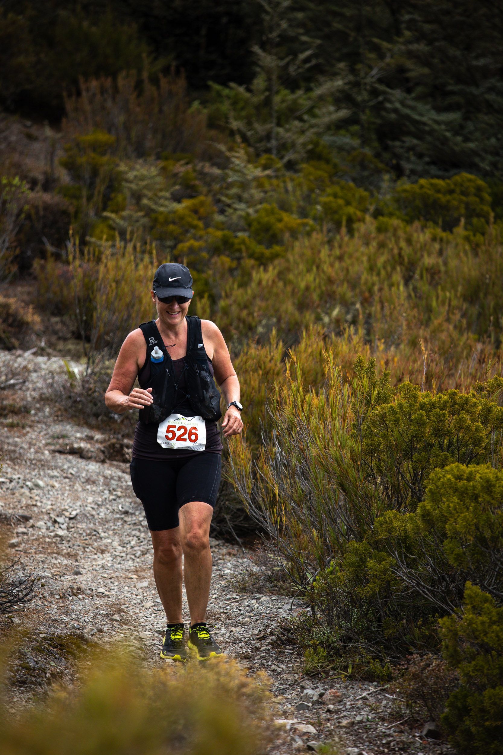 A woman is running on a trail in the woods.