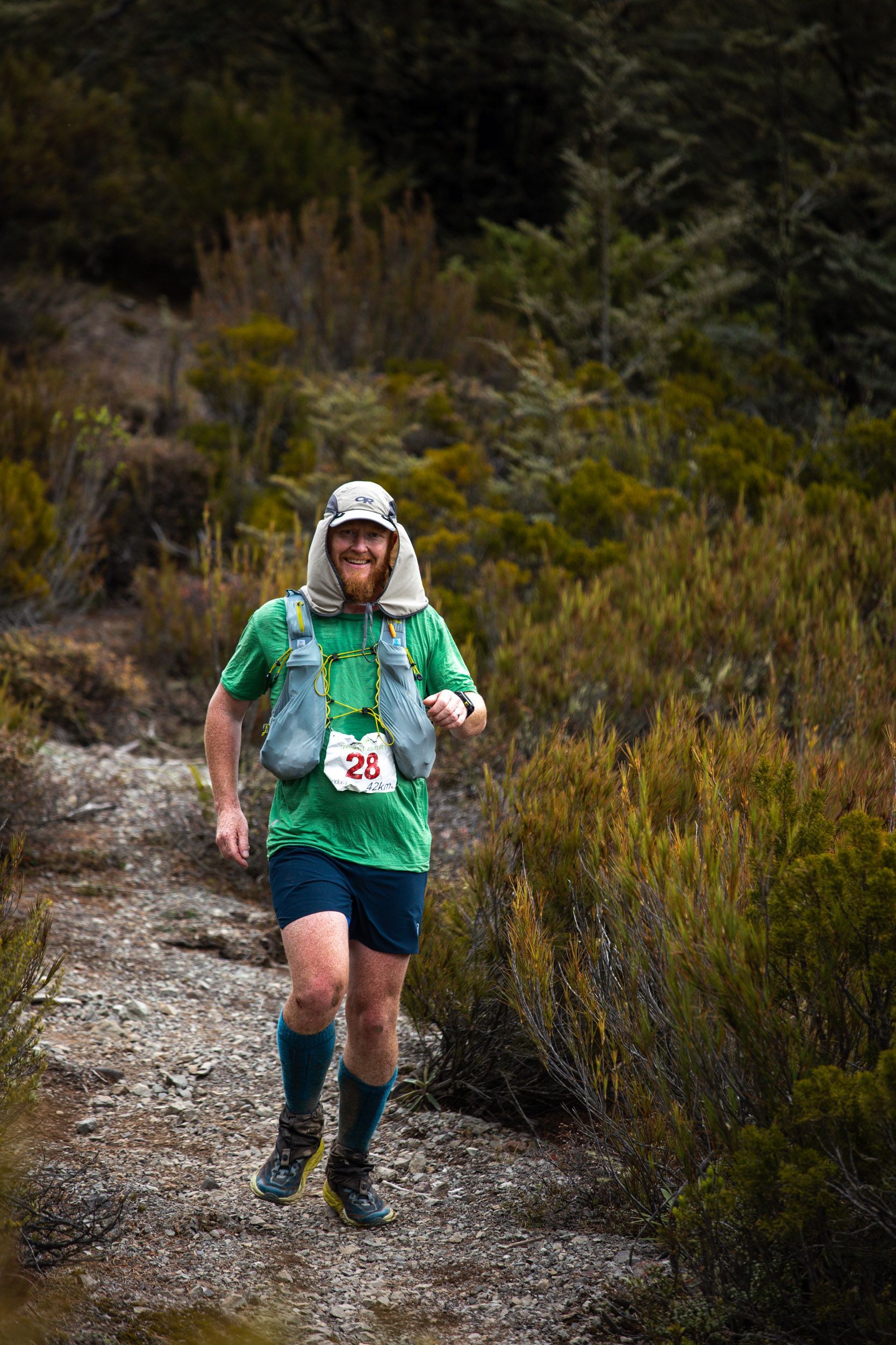A man is running on a trail in the woods.
