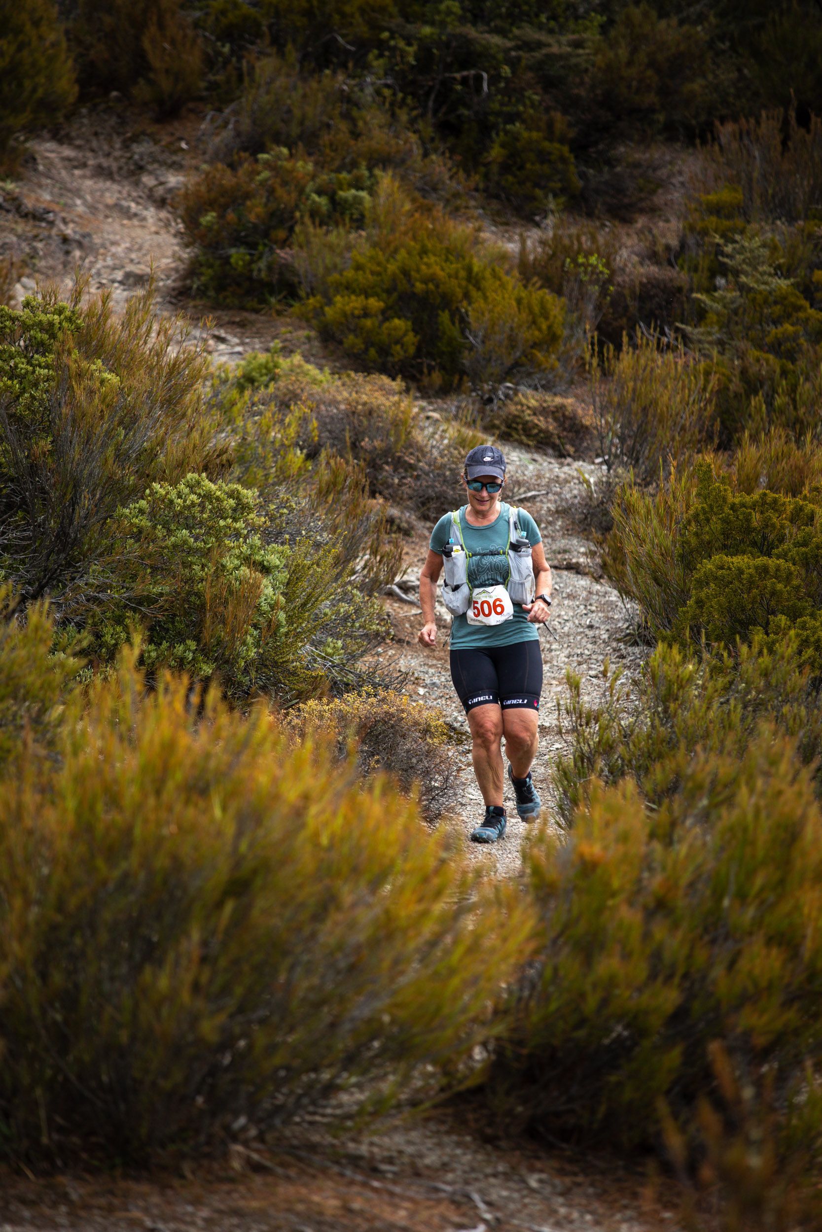 A man is running down a trail in the woods.