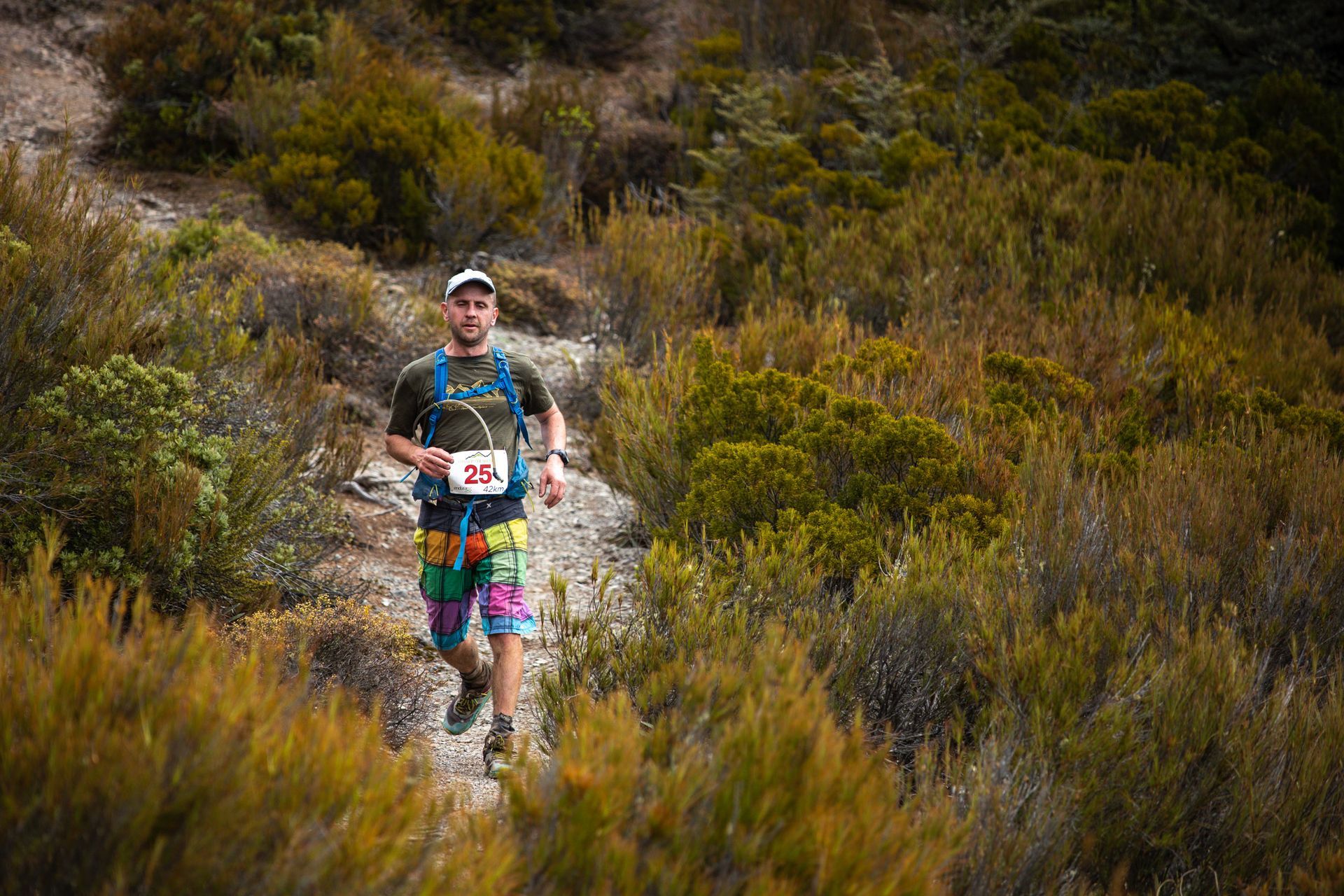 A man is running down a trail in the woods.