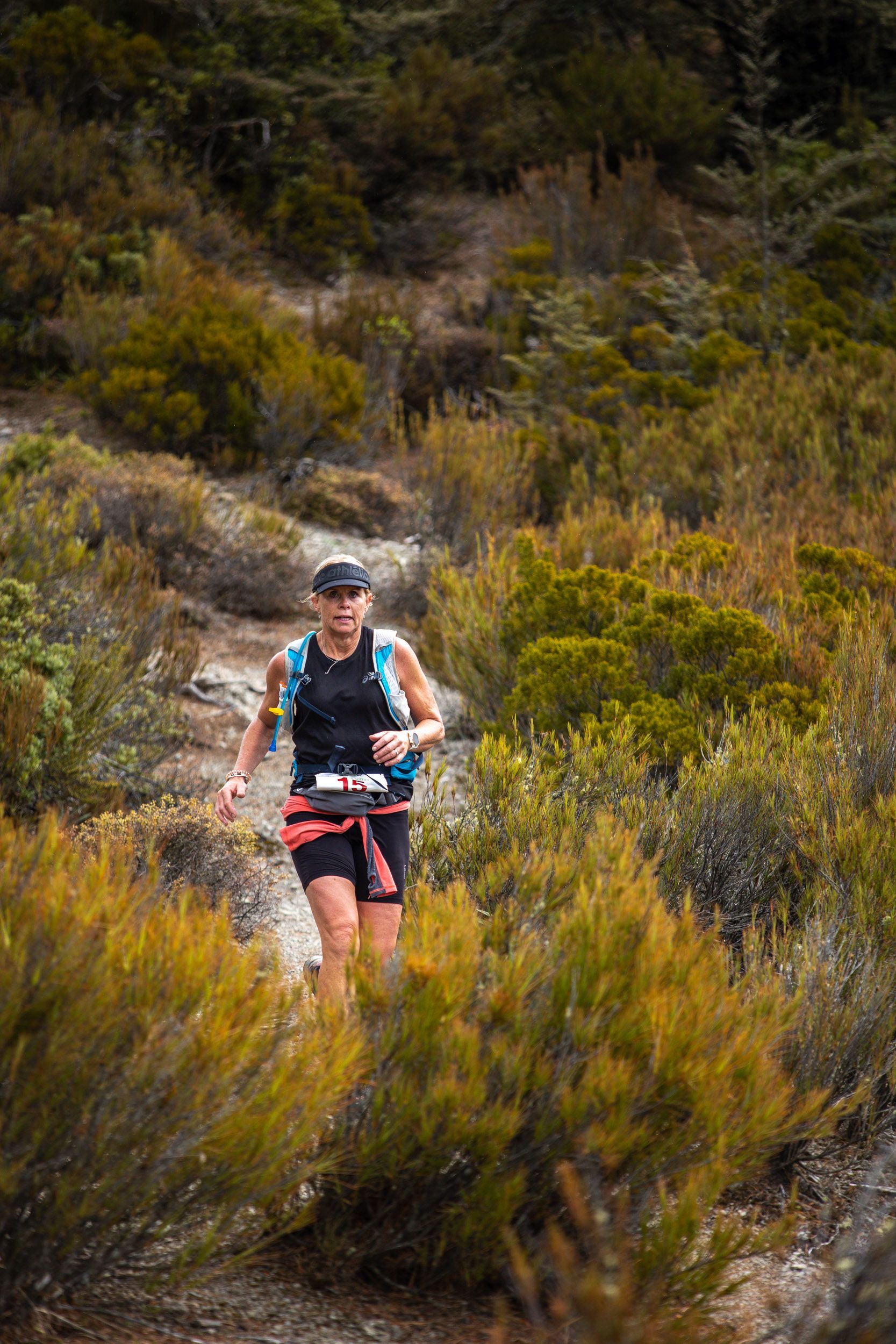 A woman is running on a trail in the woods.