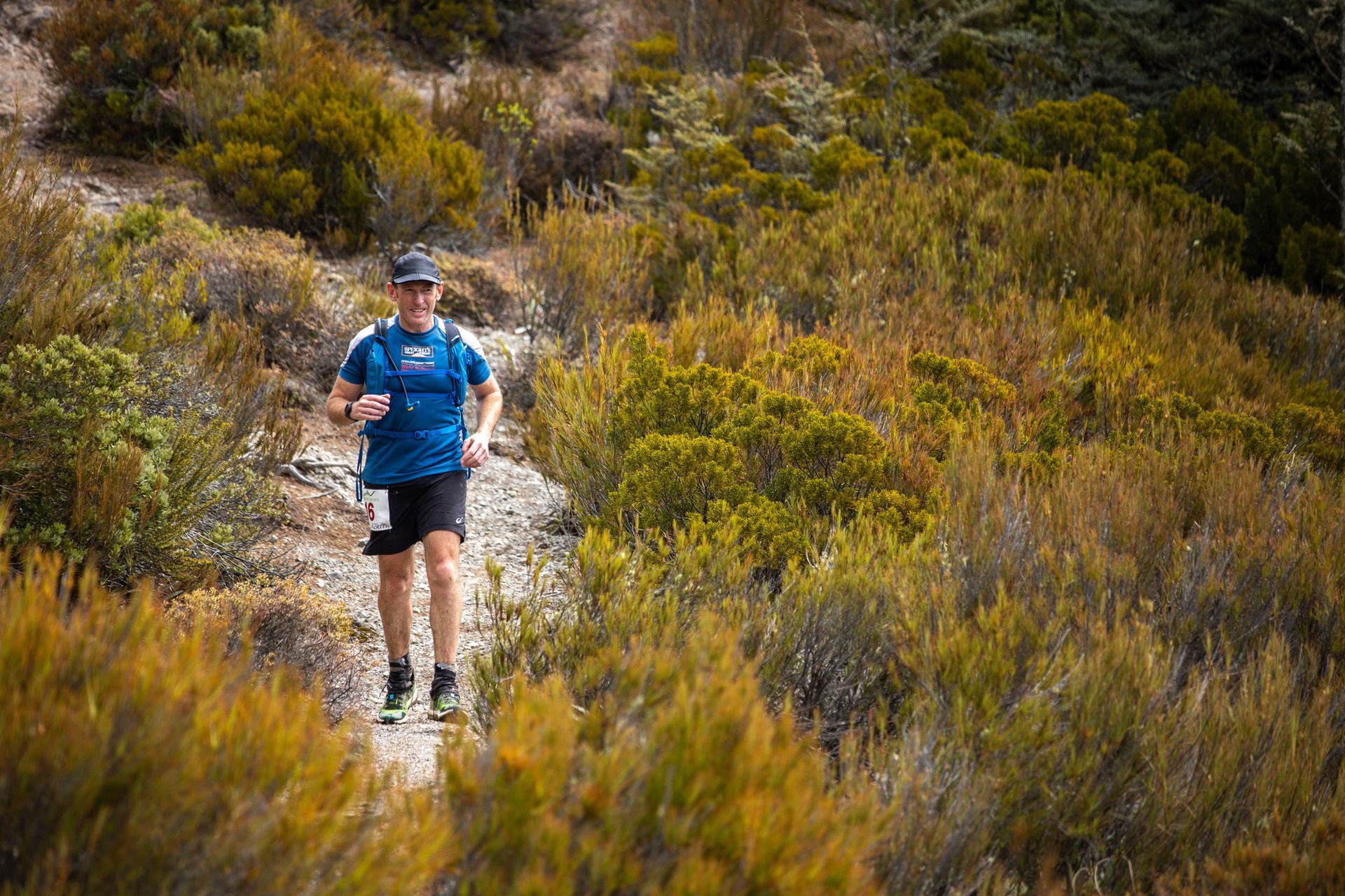 A man is running on a trail in the woods.