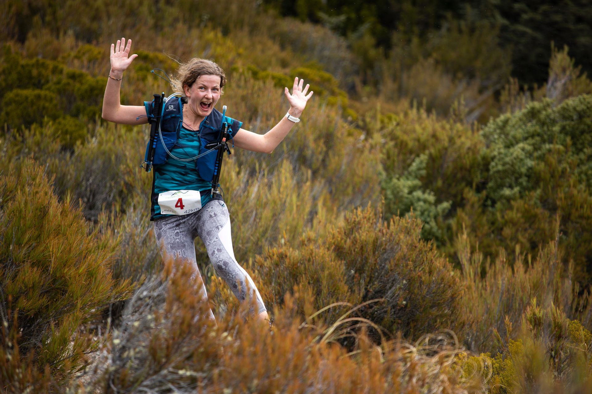 A woman is jumping over a rock in the woods.