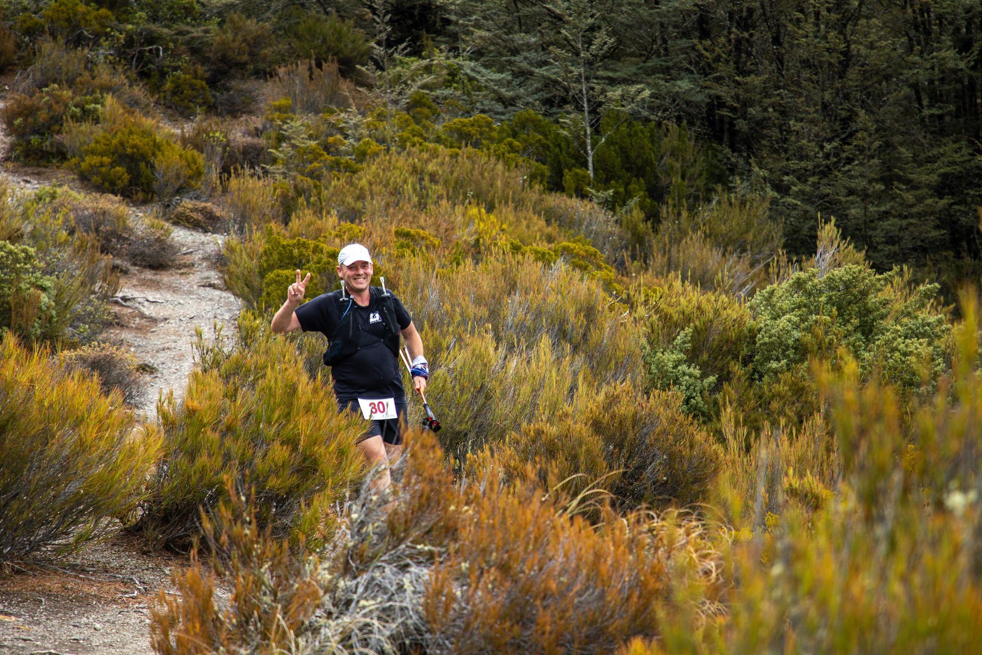 A man is running down a trail in the woods.