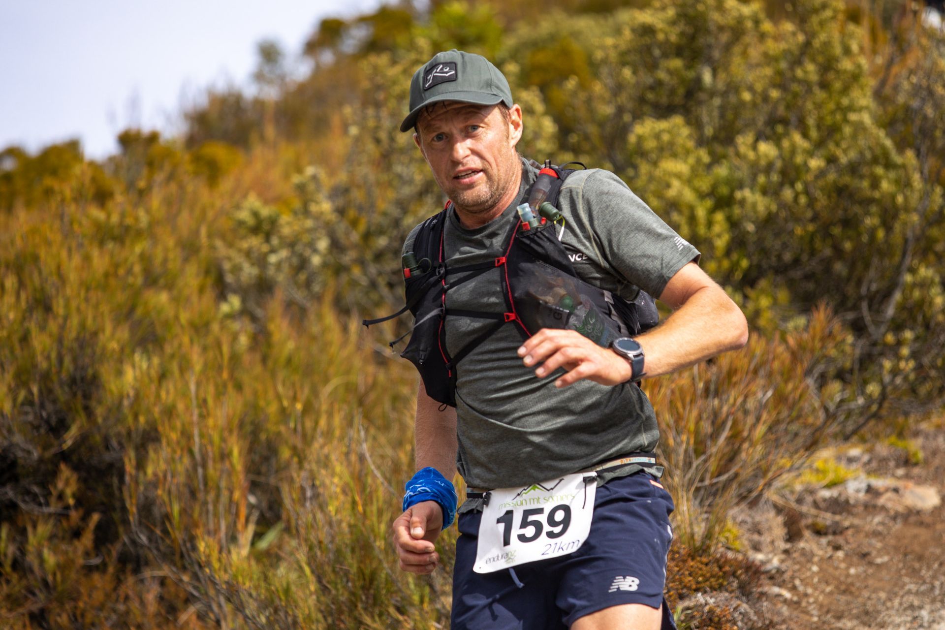A man is running on a trail in the woods.