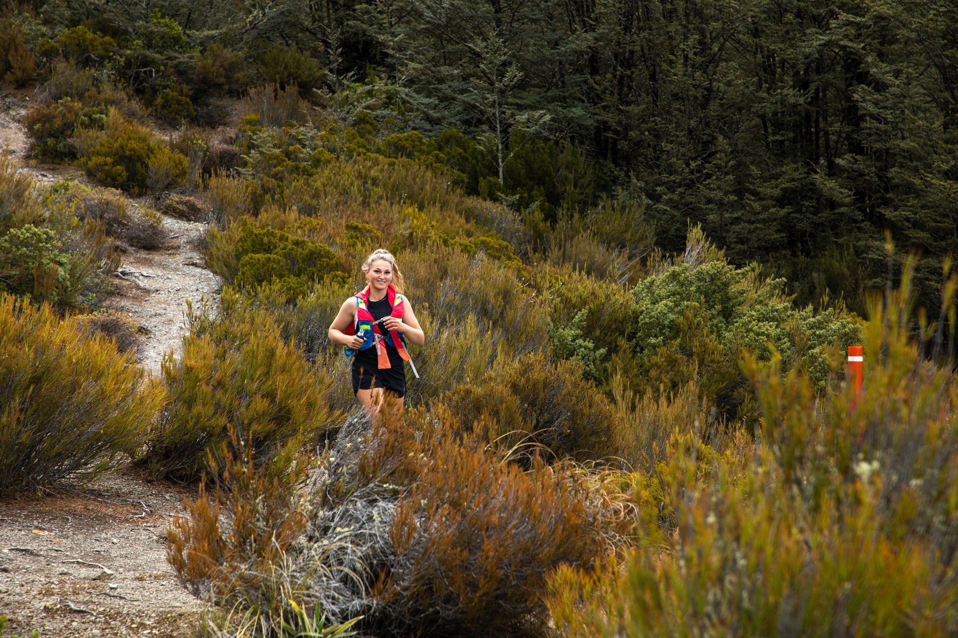 A woman is running on a trail in the woods.