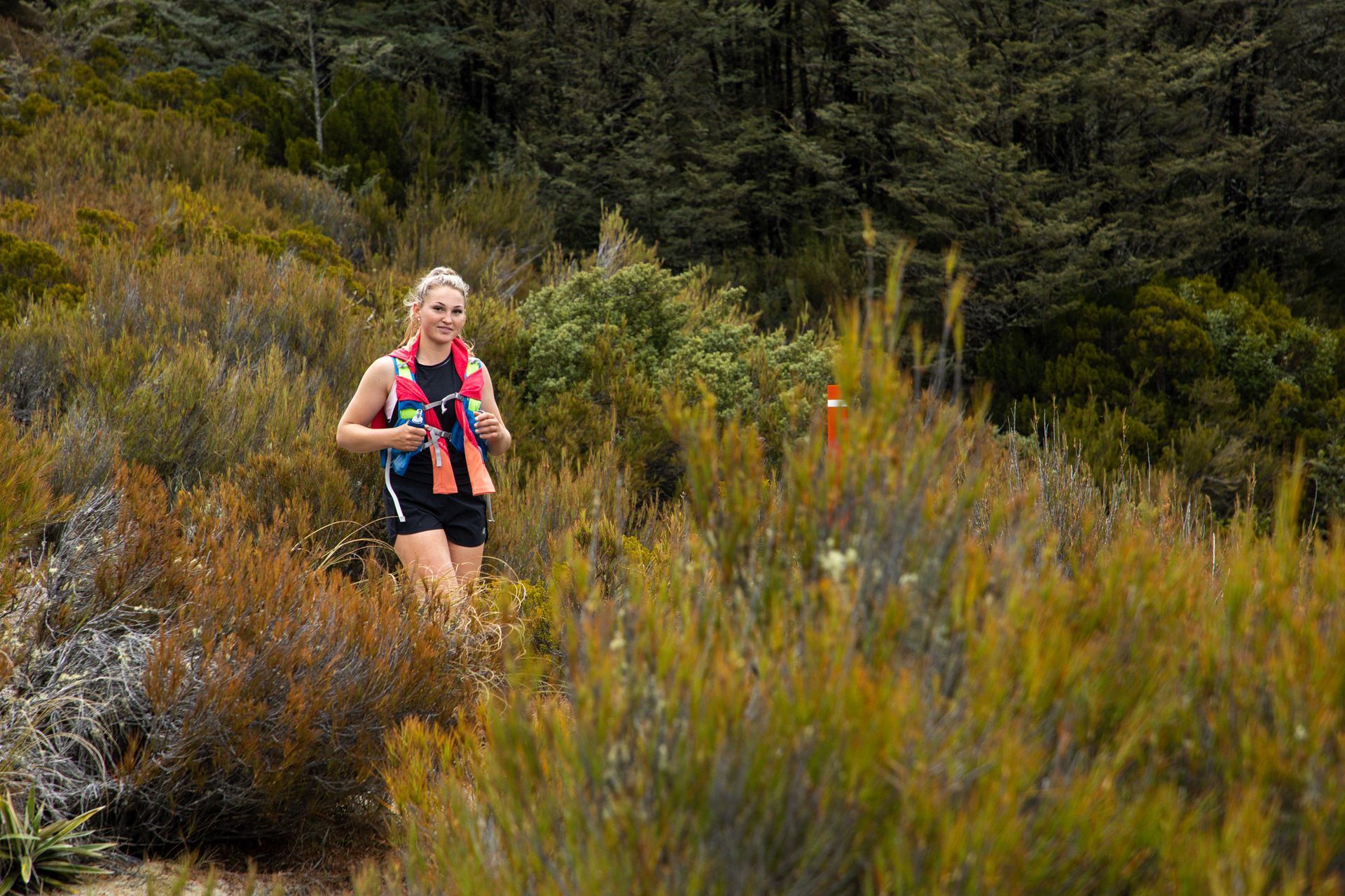 A woman is running through a lush green field.