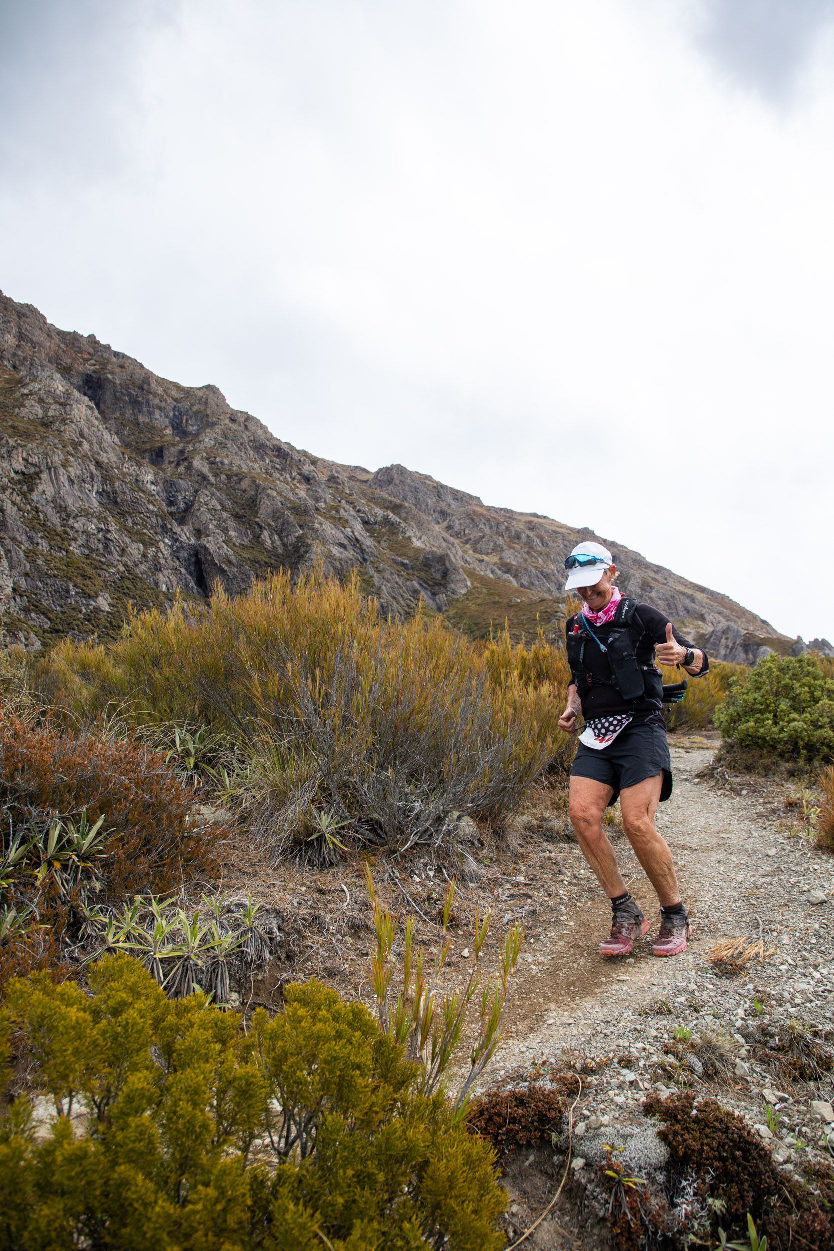 A man is running on a trail in the mountains.