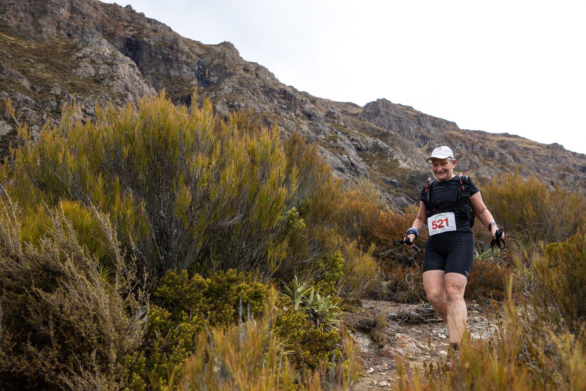 A woman is running on a trail in the mountains.