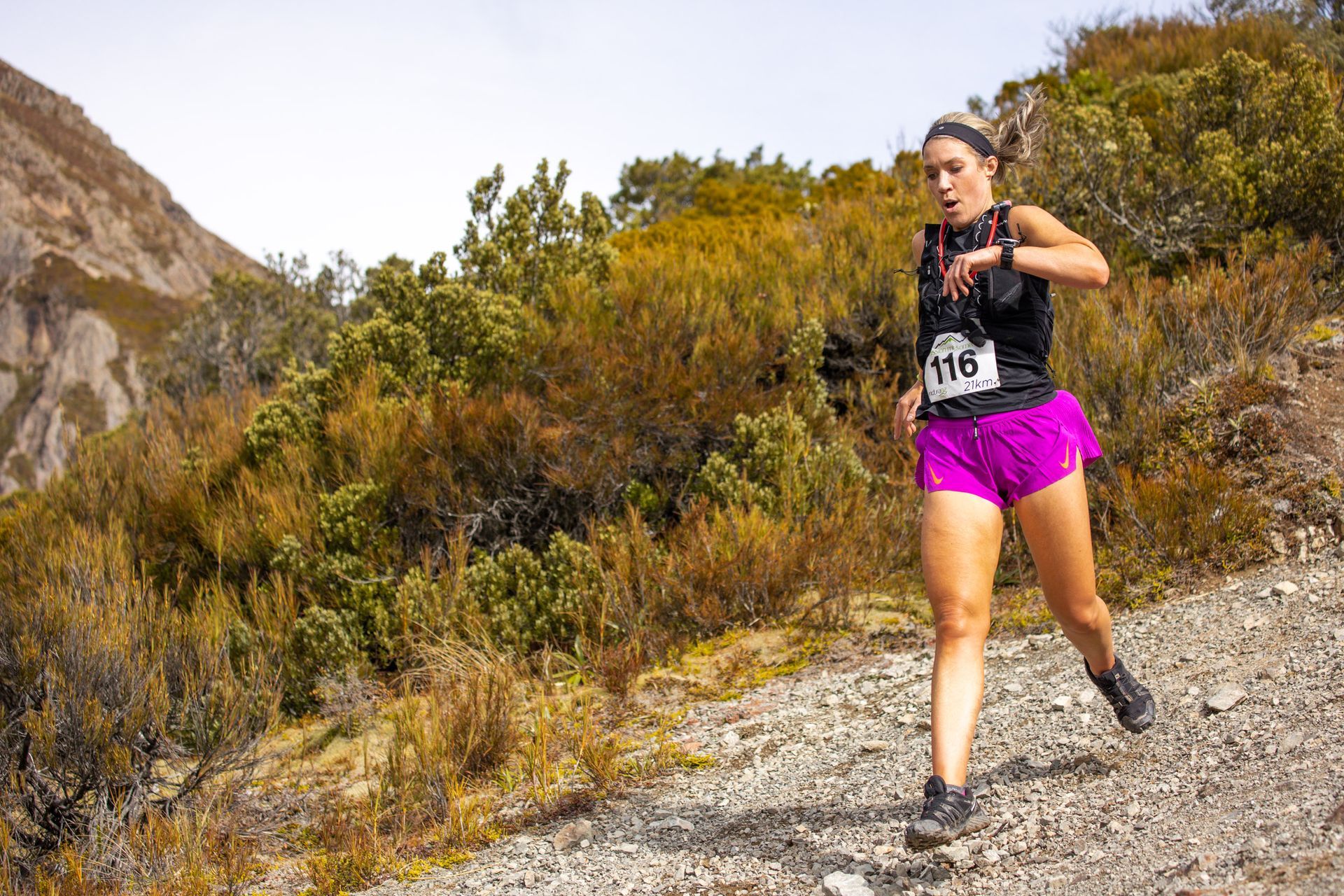 A woman is running on a trail in the mountains.
