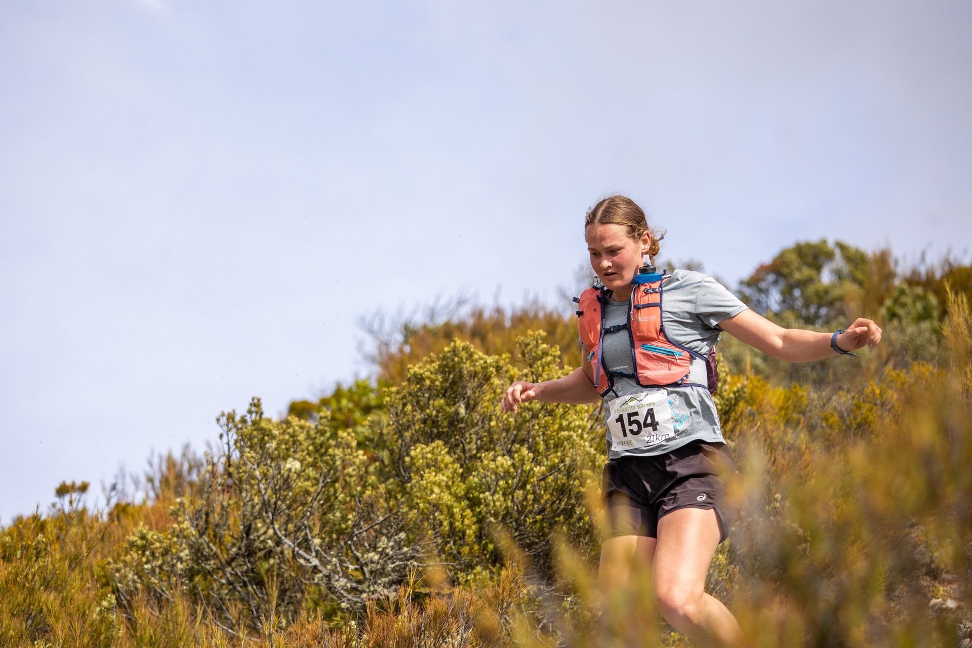 A woman is running on a trail in the woods.