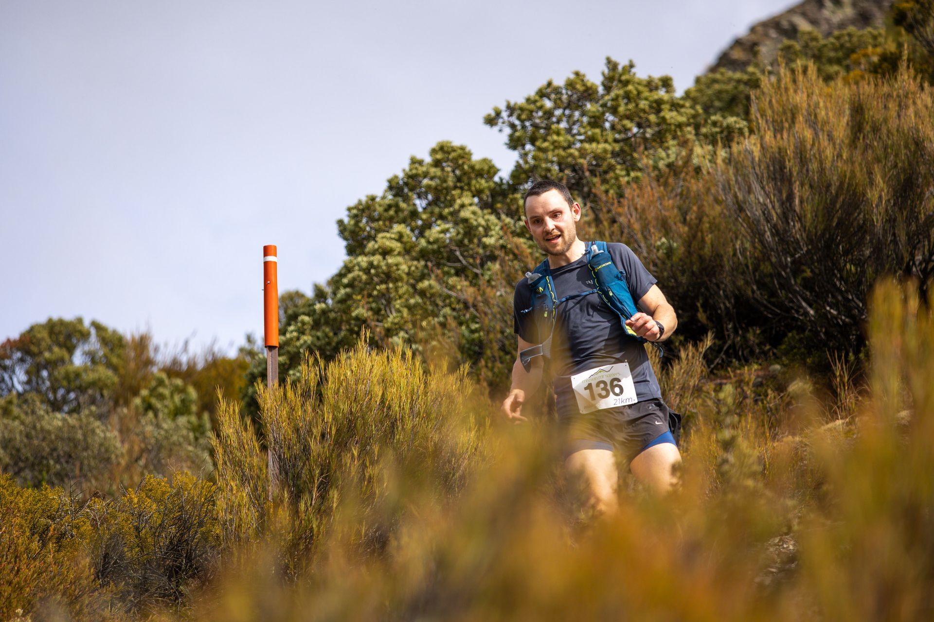 A man is running on a trail in the woods.