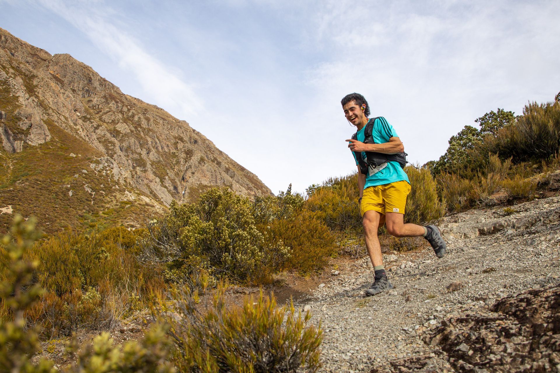 A man is running on a trail in the mountains.