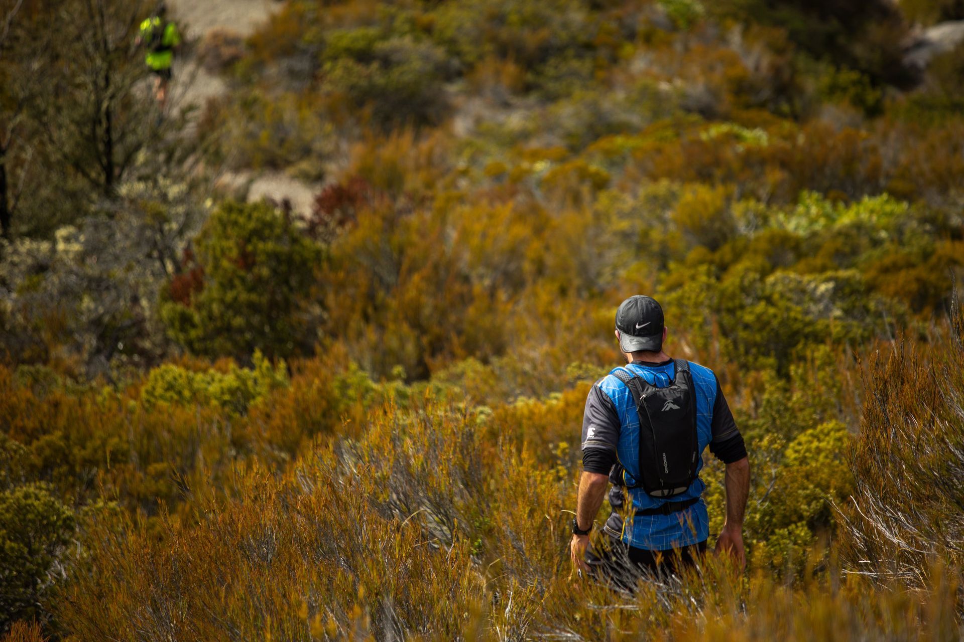 A man with a backpack is walking through a field.
