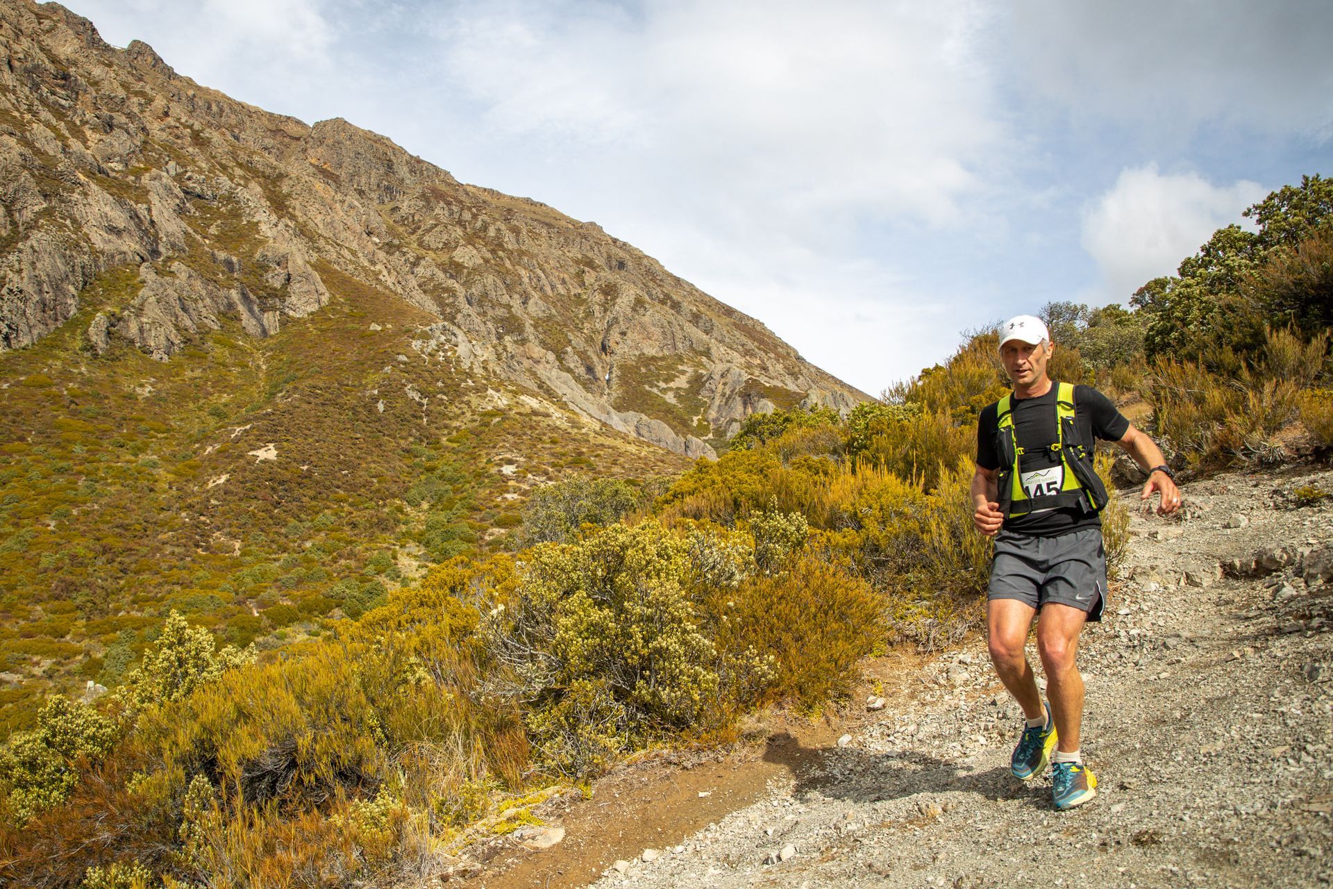 A man is running on a trail in the mountains.
