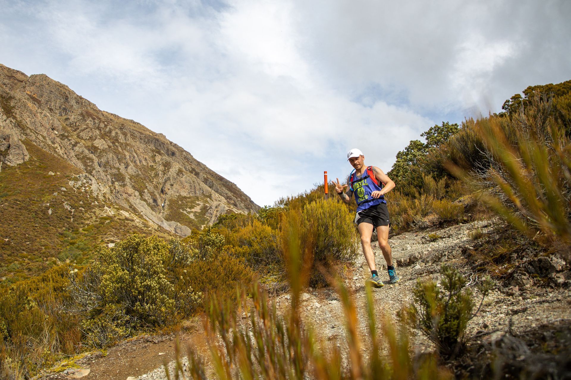 A man is running on a trail in the mountains.