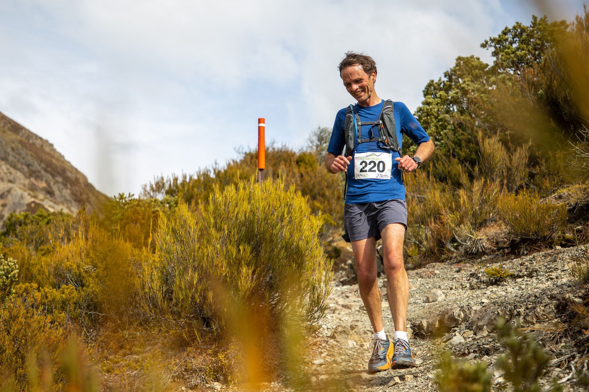 A man is running on a trail in the mountains.