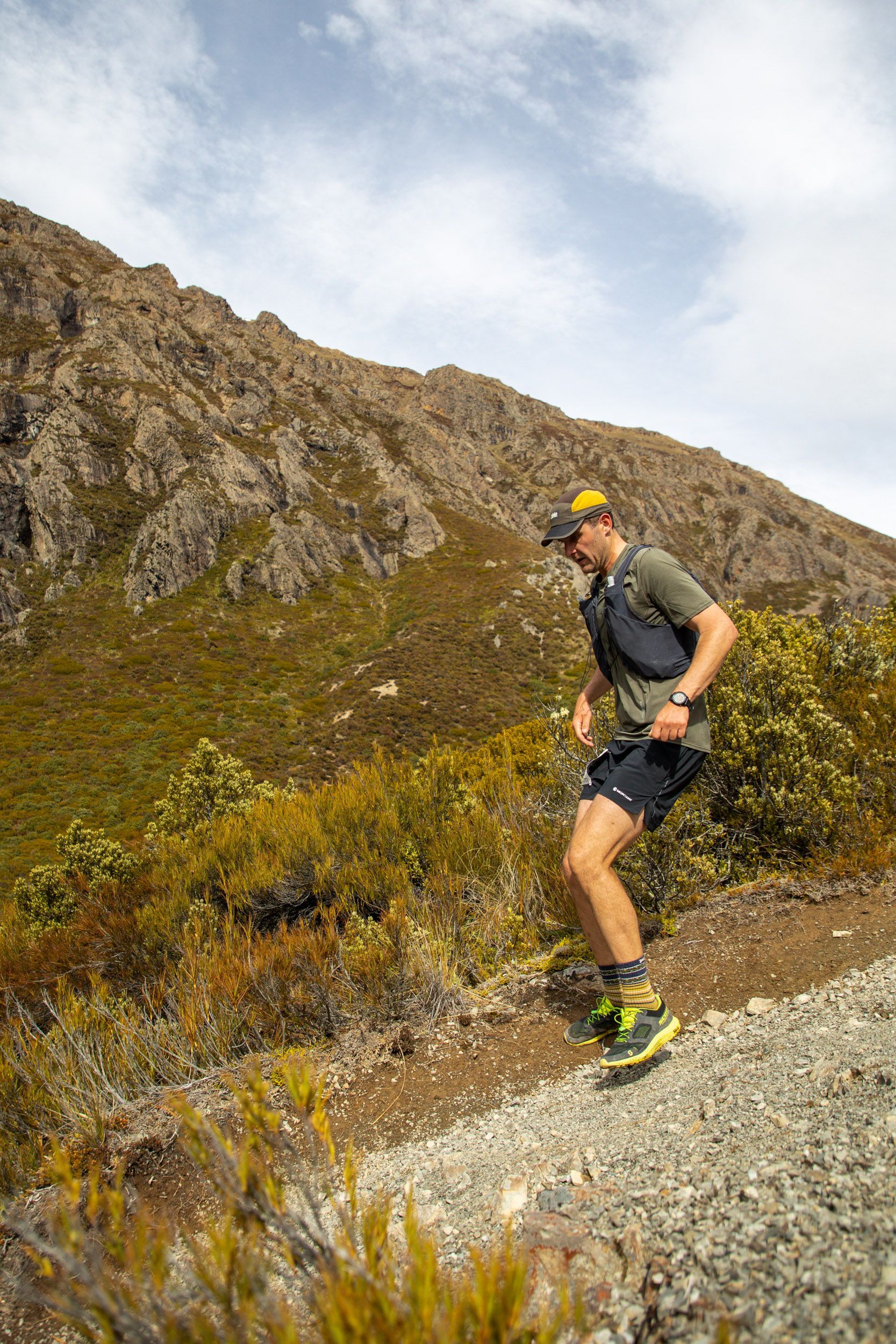 A man is running on a trail in the mountains.