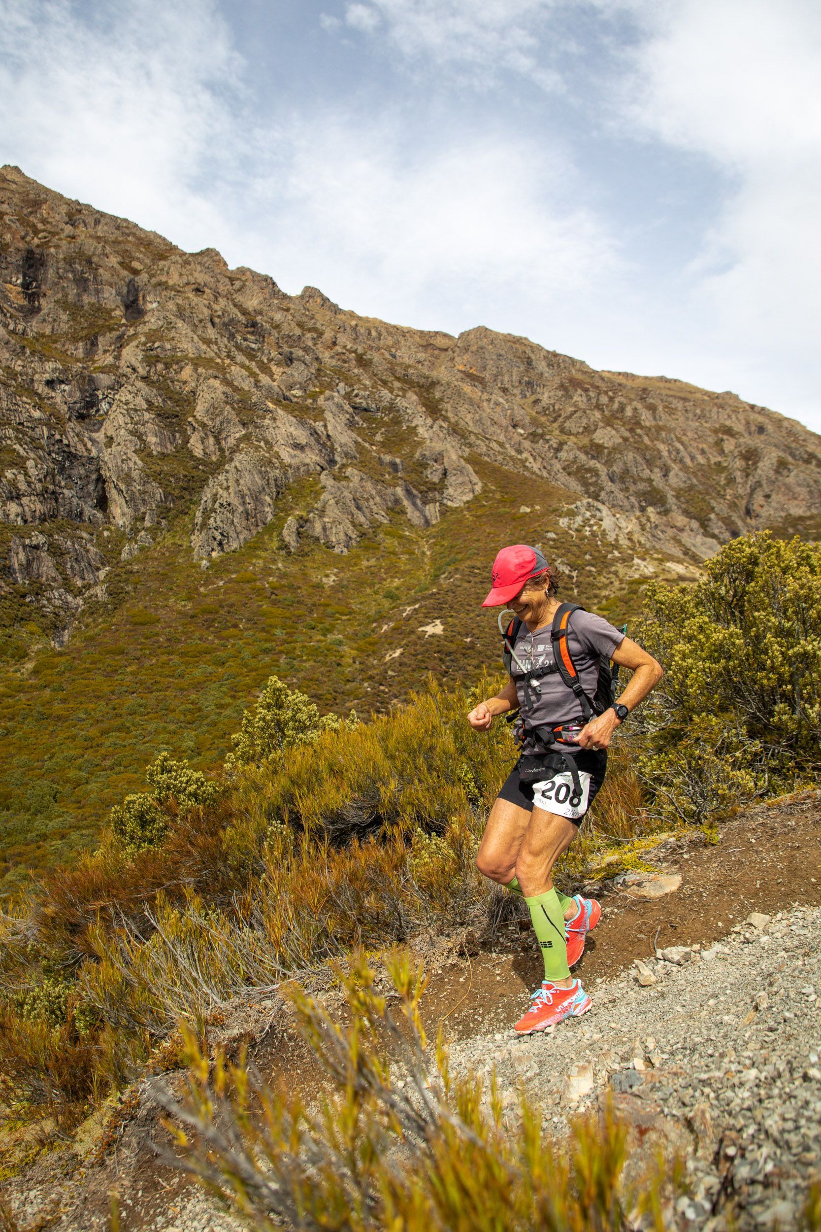 A man is running on a trail in the mountains.