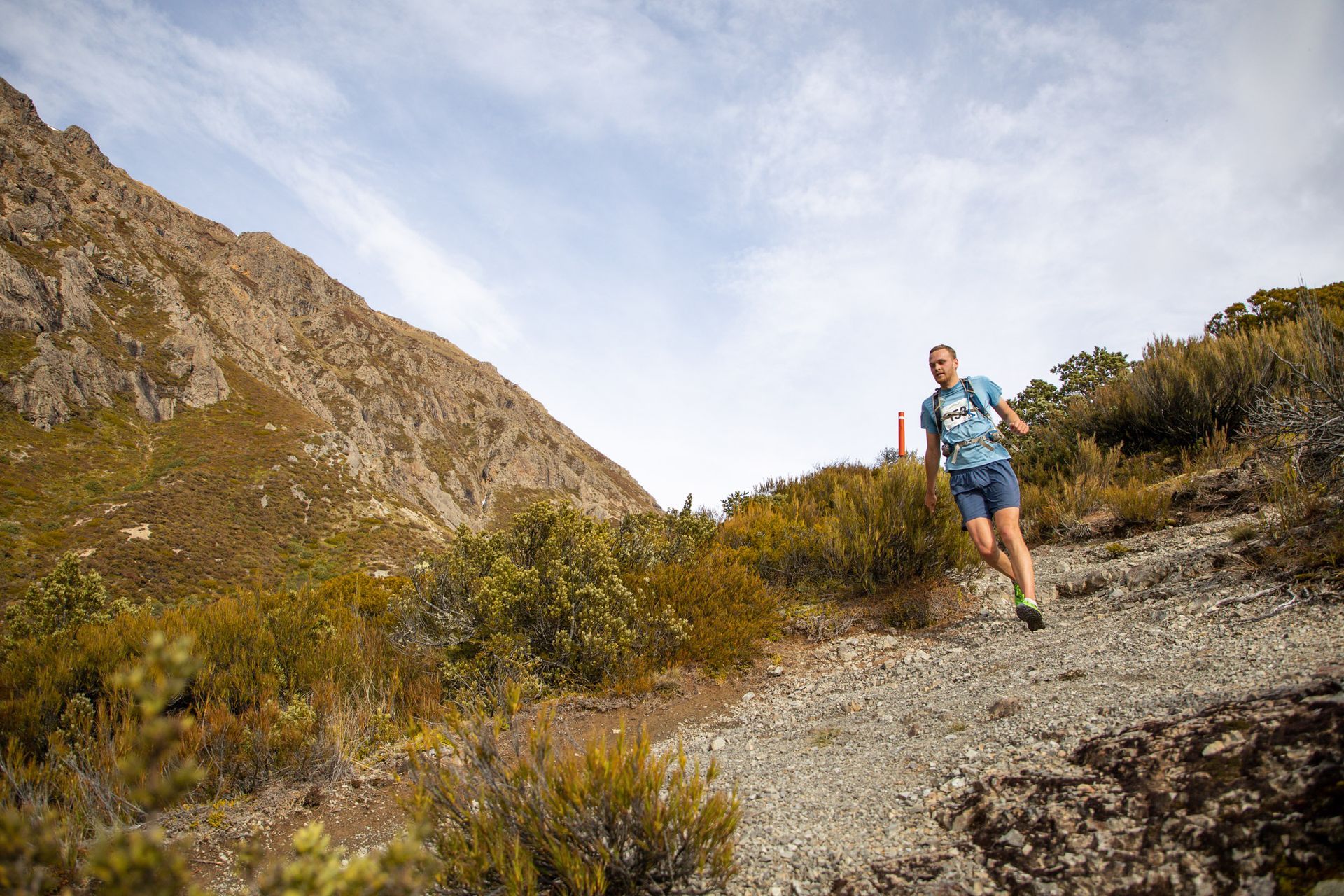 A man is running down a dirt path in the mountains.