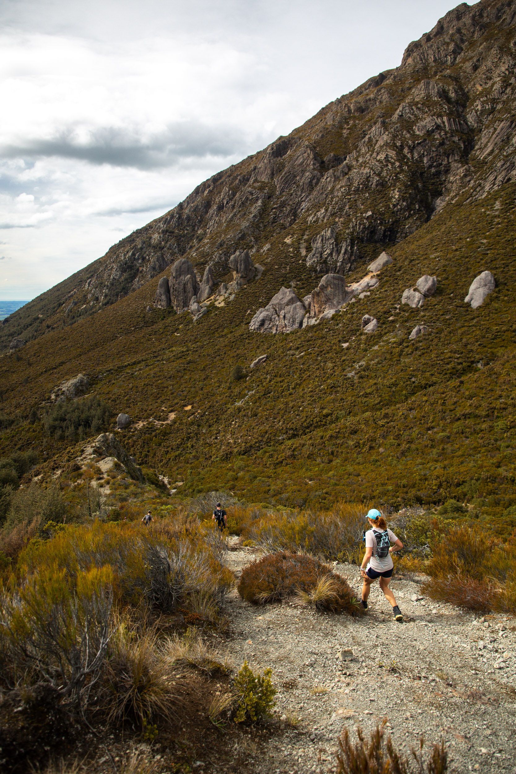 A person is walking down a dirt path in the mountains.