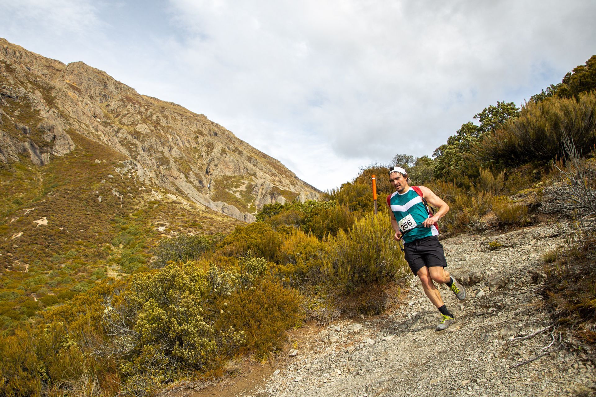 A man is running down a dirt trail in the mountains.