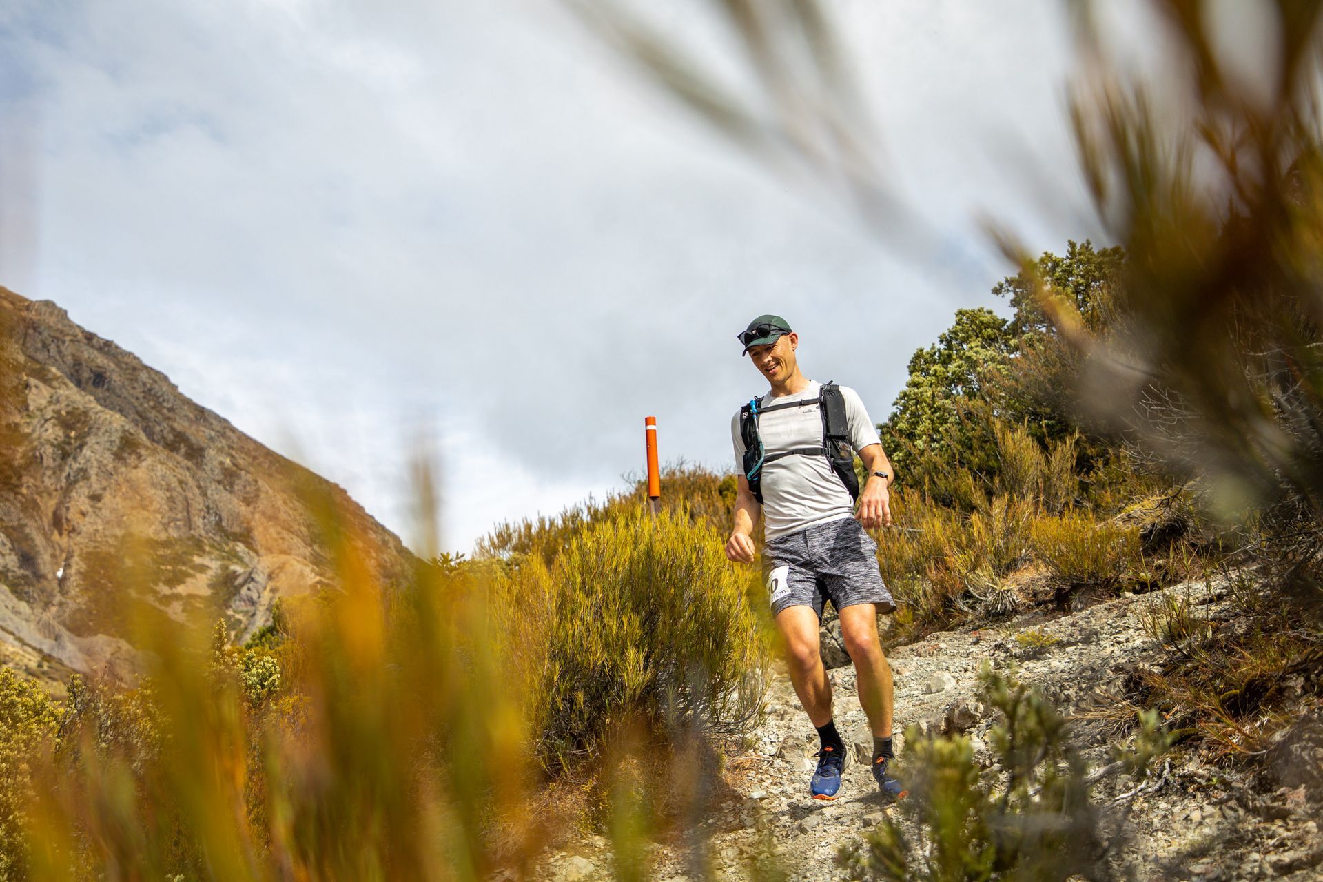 A man with a backpack is running up a hill.