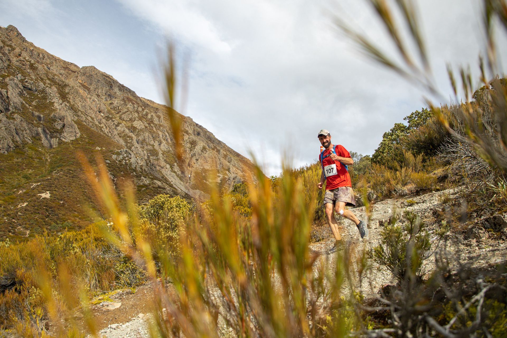 A man is running on a trail in the mountains.